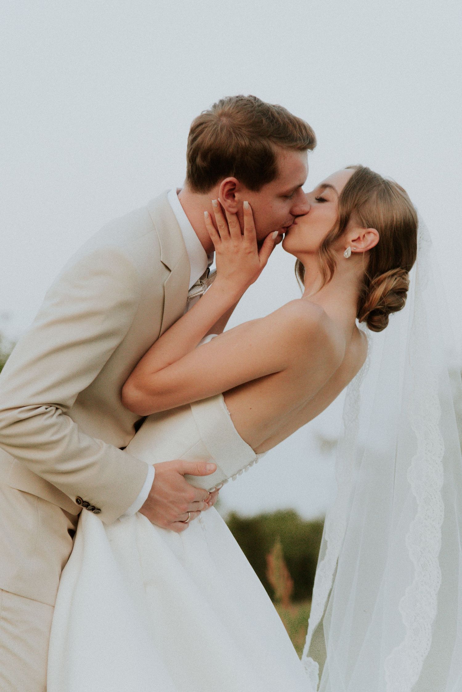 A romantic wedding kiss sequence showing the newlyweds sharing their first kiss in beige and white attire.