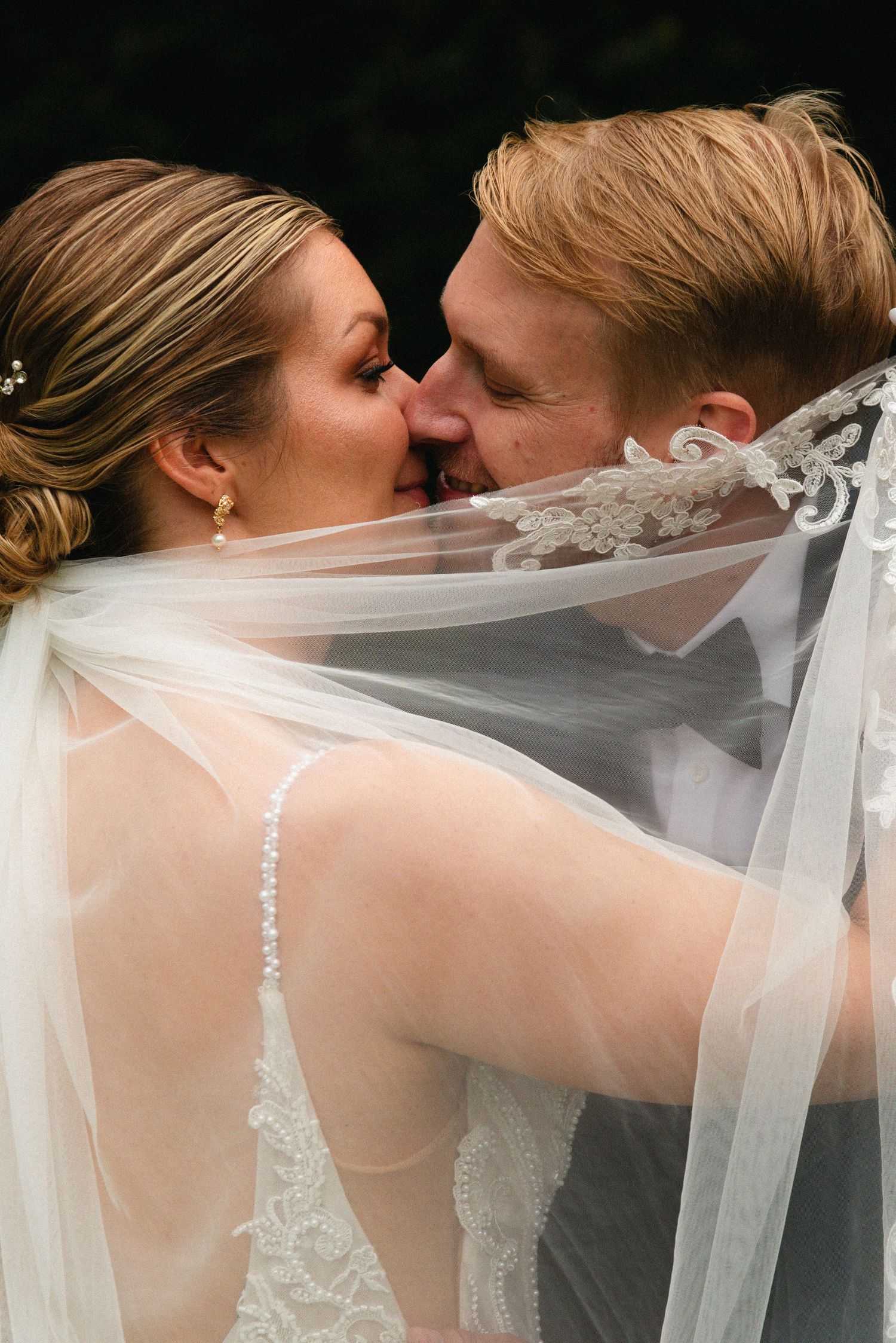 Close-up sequence of a romantic kiss through a delicate white wedding veil.