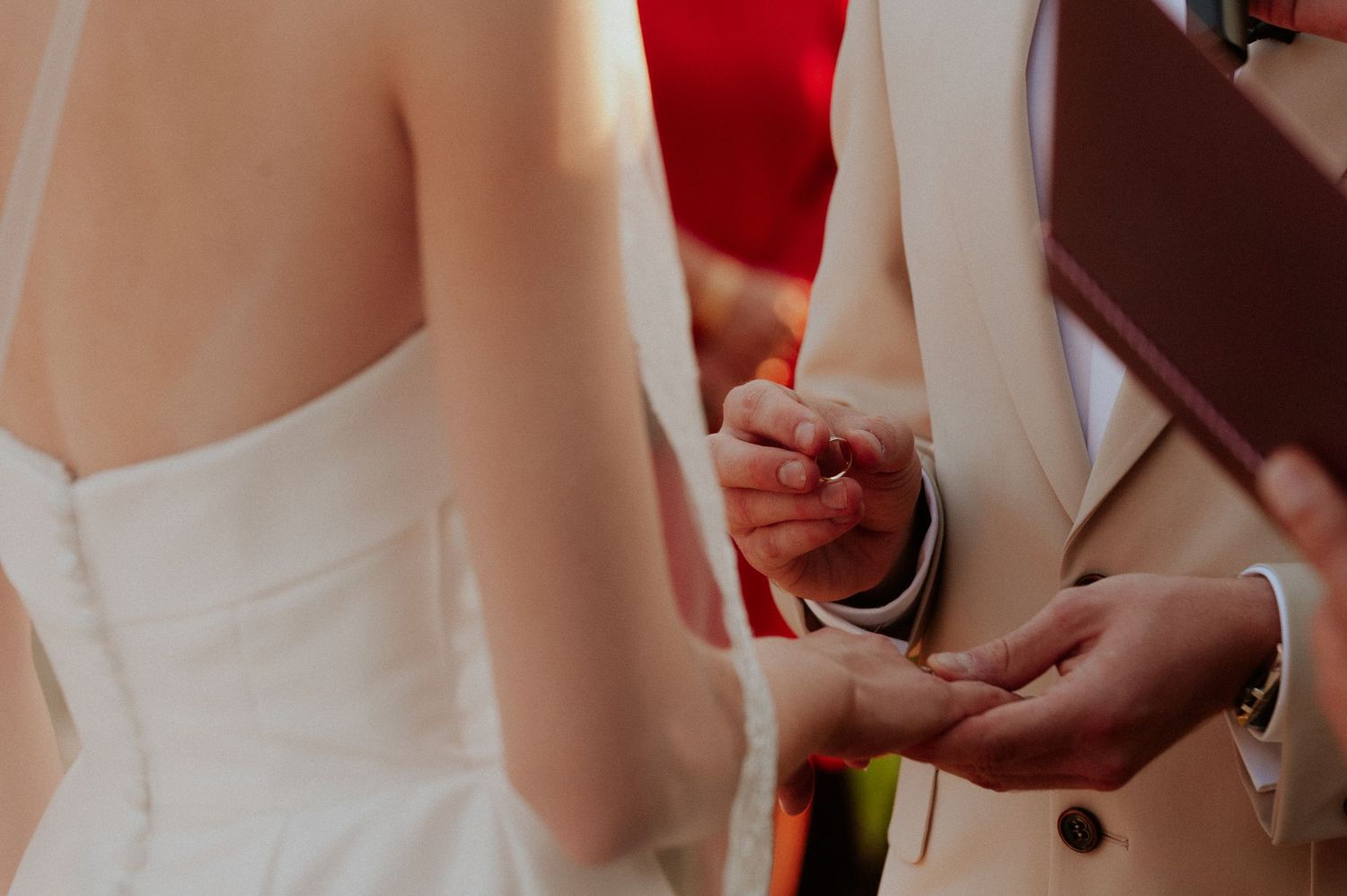 Close-up view of hands exchanging wedding rings during a traditional ceremony.
