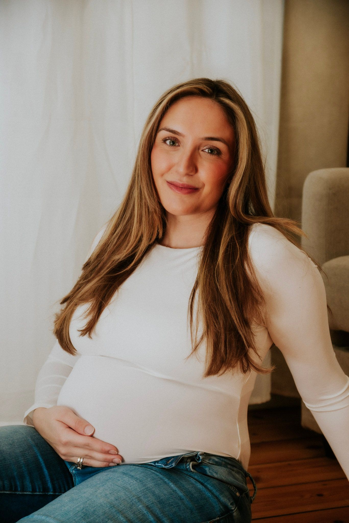 A series of lifestyle portraits showing a person in a white sweater and jeans relaxing on hardwood floors.