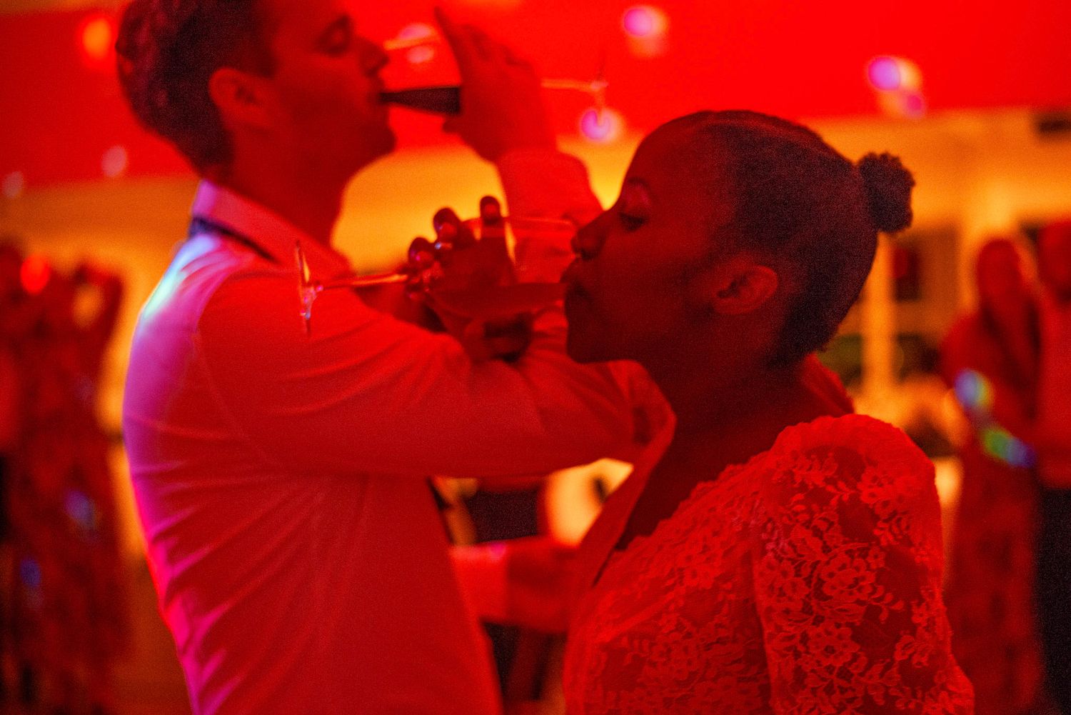 Romantic dance scene bathed in dramatic red lighting at a wedding reception.