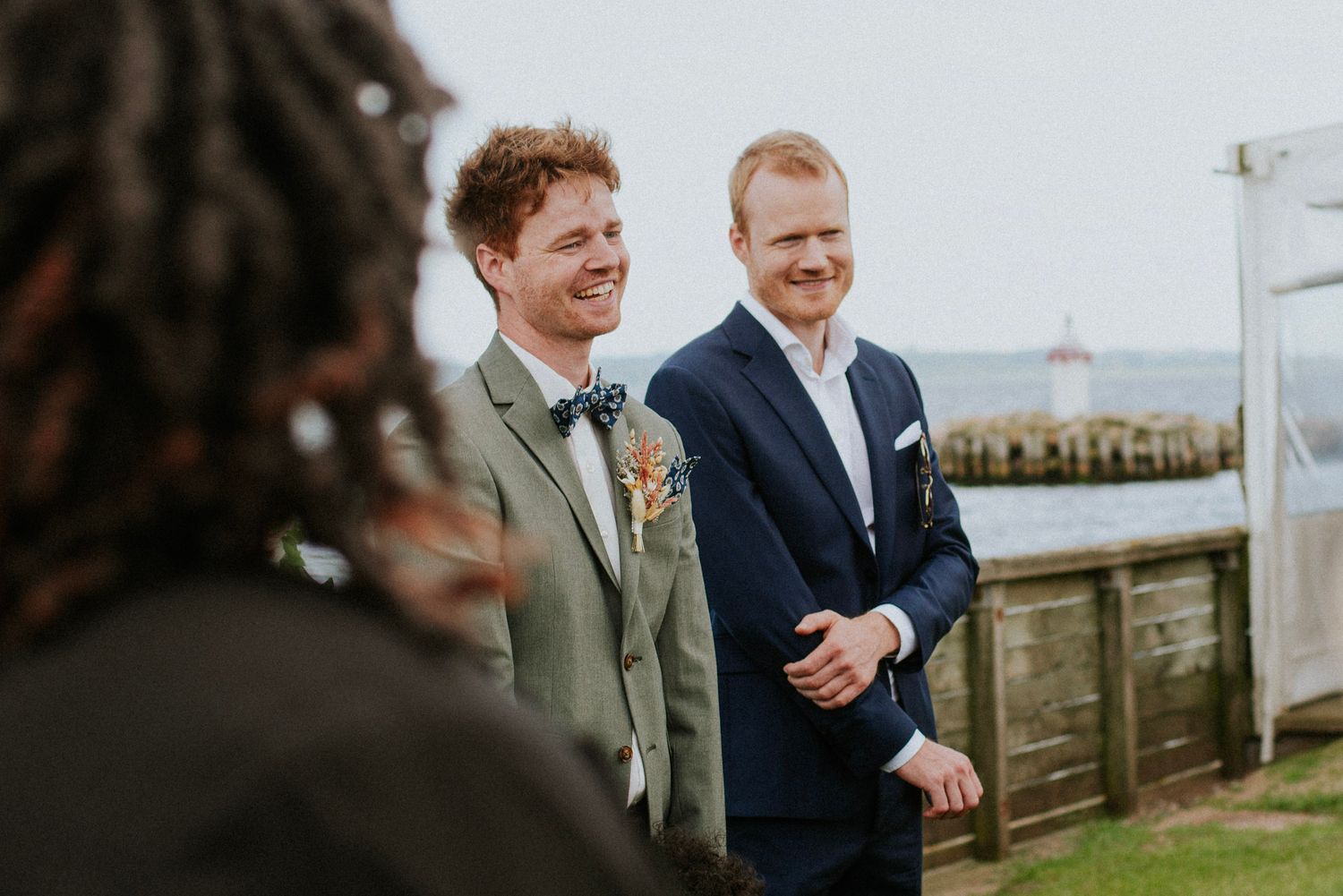Wedding party shares candid laughs during outdoor photo session near the waterfront.