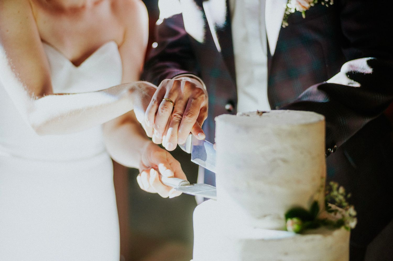 Close-up shots of traditional white wedding cake being cut during reception.