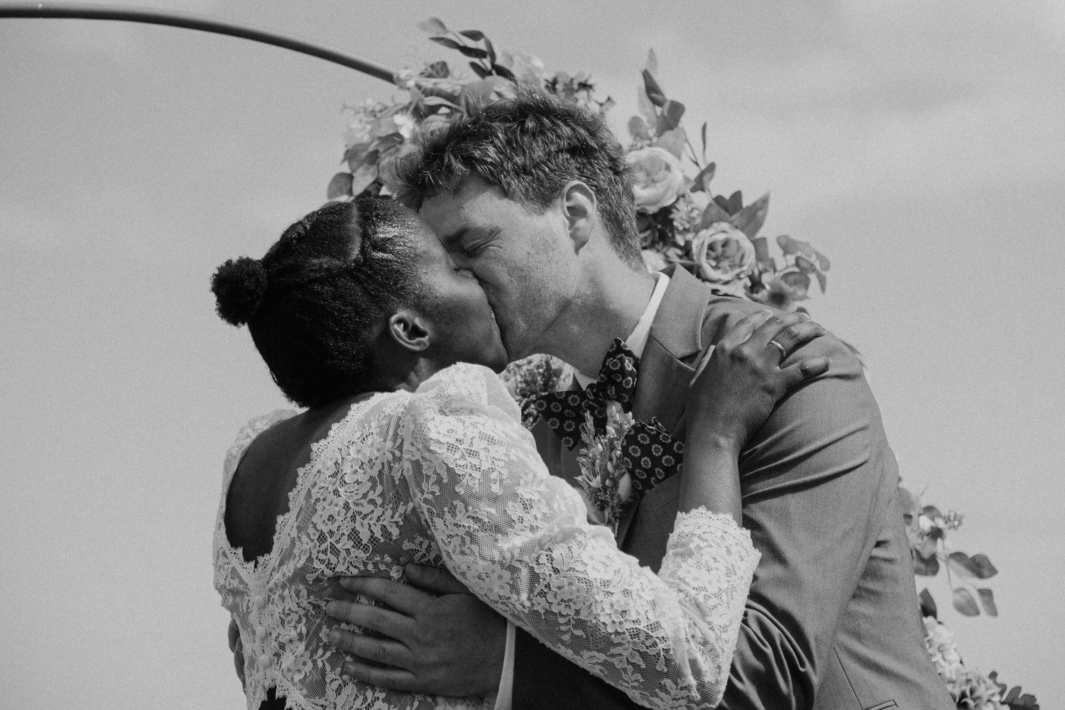 Dramatic black and white portrait of newlyweds sharing an intimate moment outdoors.