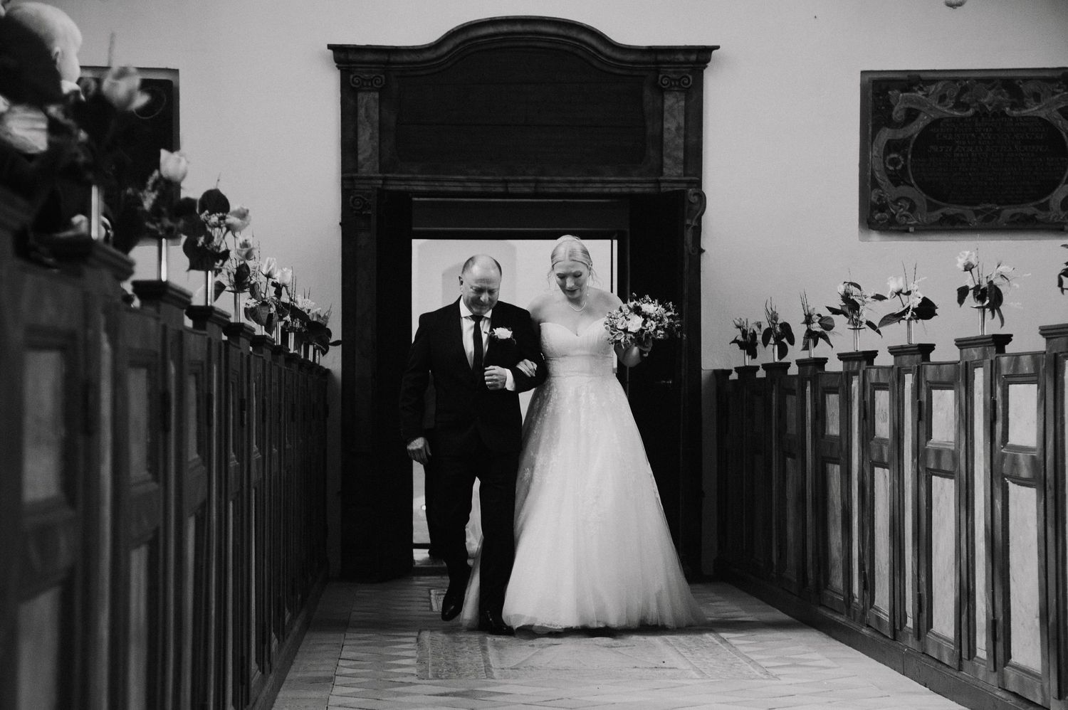 Wedding ceremony in a traditional church with wooden pews and stained glass windows.