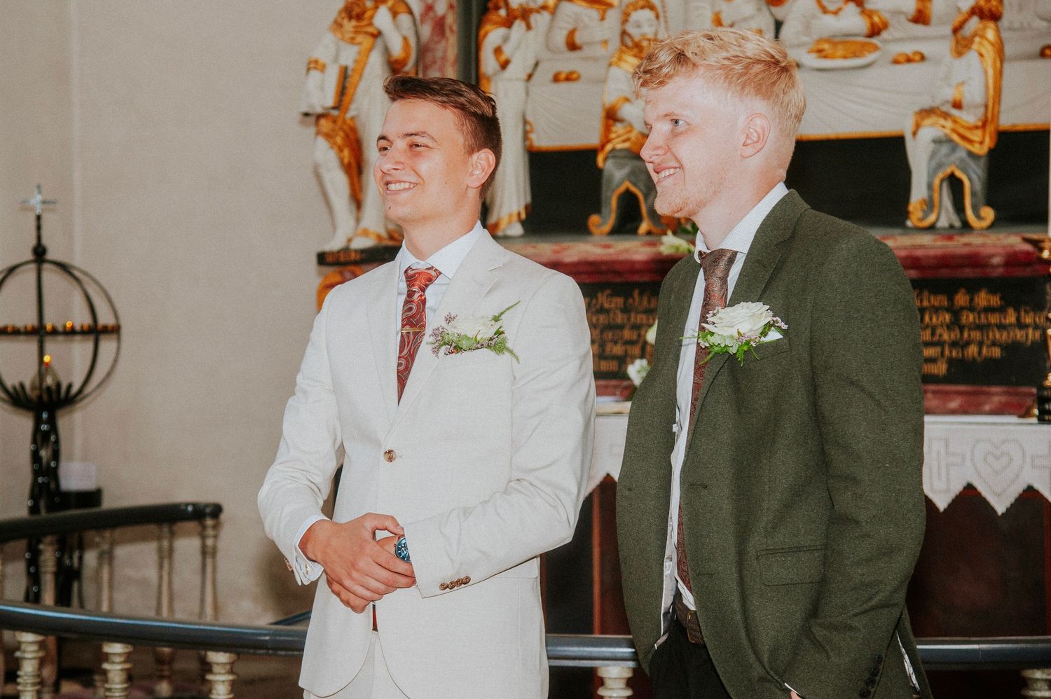 Two men in suits standing at the altar during a wedding ceremony.