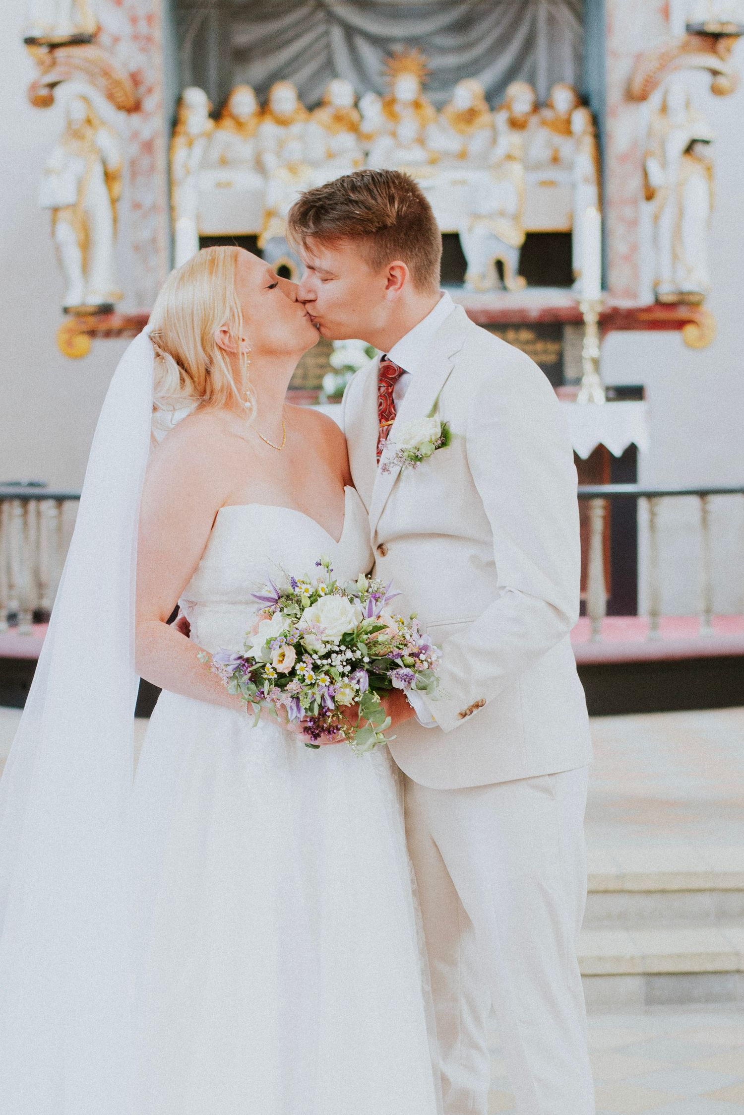 A tender moment shared between newlyweds against an ornate backdrop.