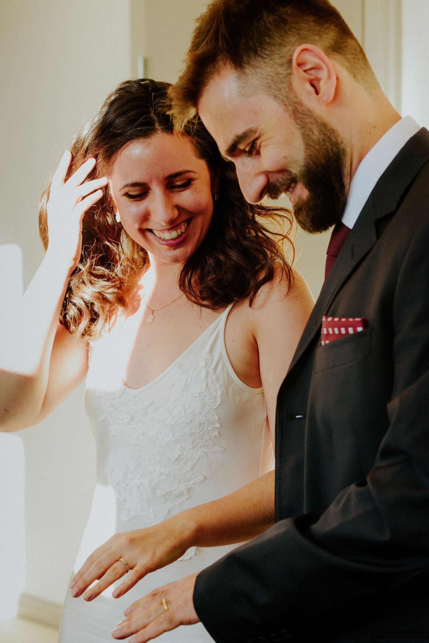 Couple in wedding attire sharing intimate moments indoors with natural lighting.