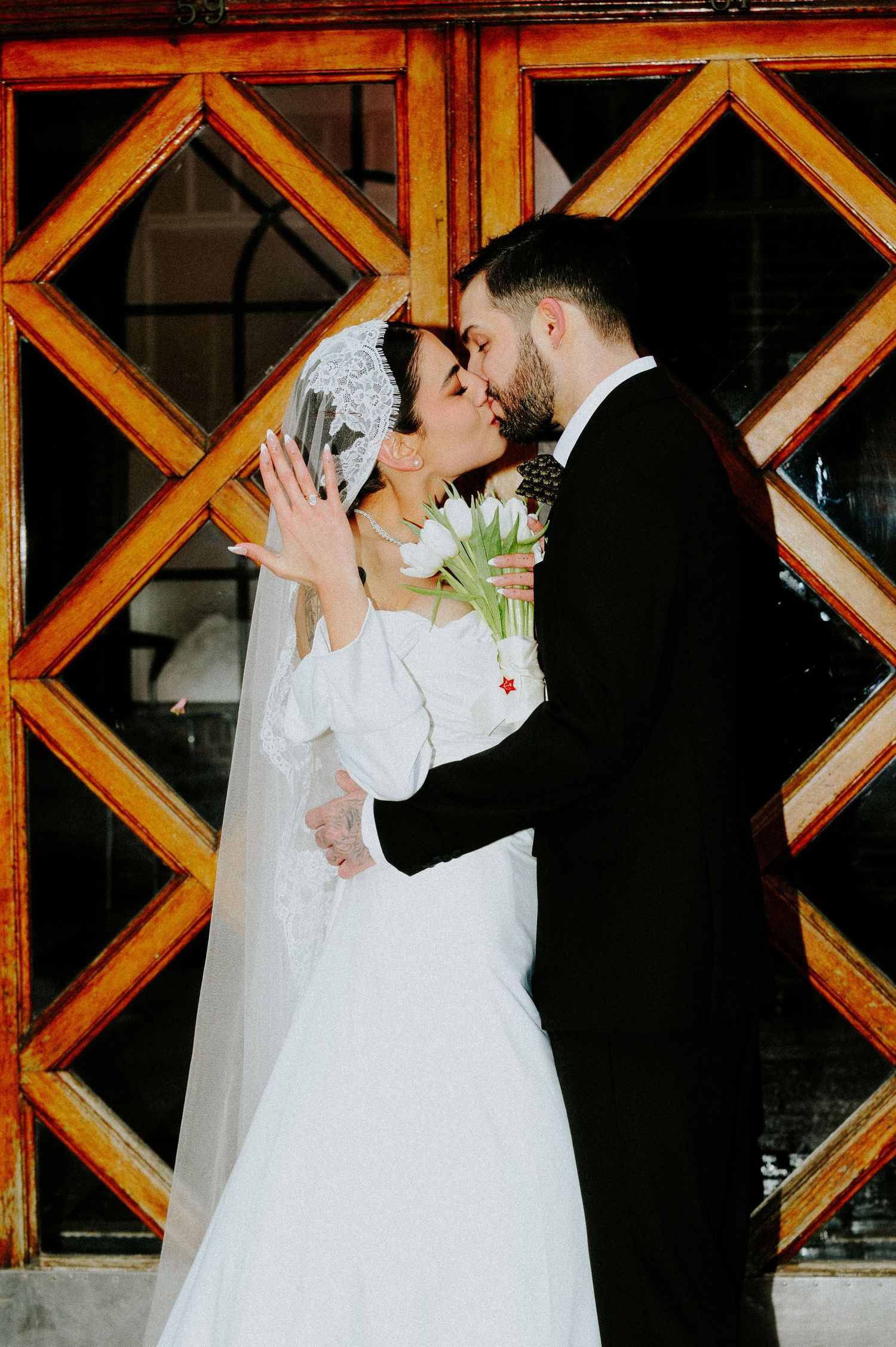 Wedding couple shares intimate moment against geometric wooden wall pattern.