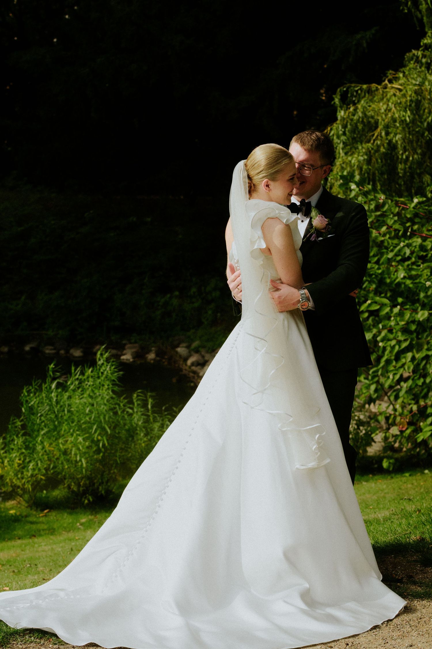 A couple in wedding attire share romantic moments in a garden setting.