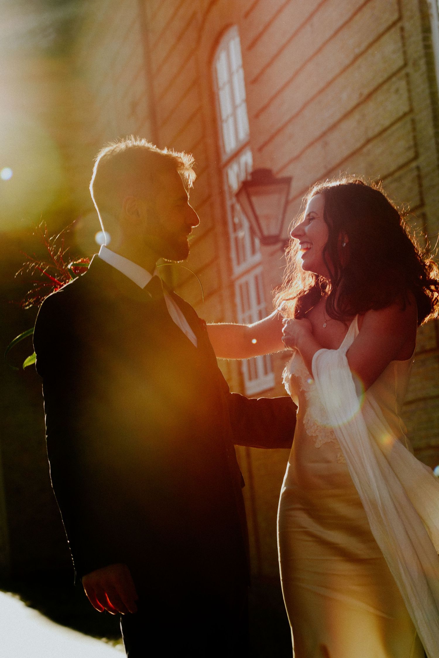 Silhouettes of figures against a warm sunset glow with lens flare and architectural elements.
