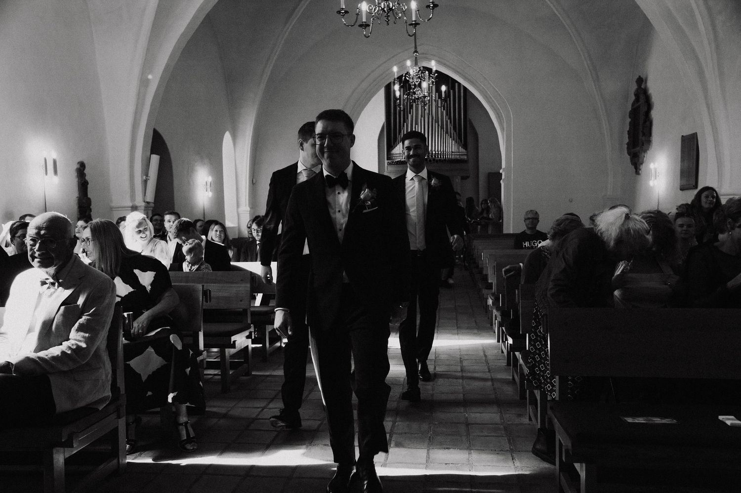 Black and white photograph showing guests dancing and mingling at an elegant indoor reception venue.