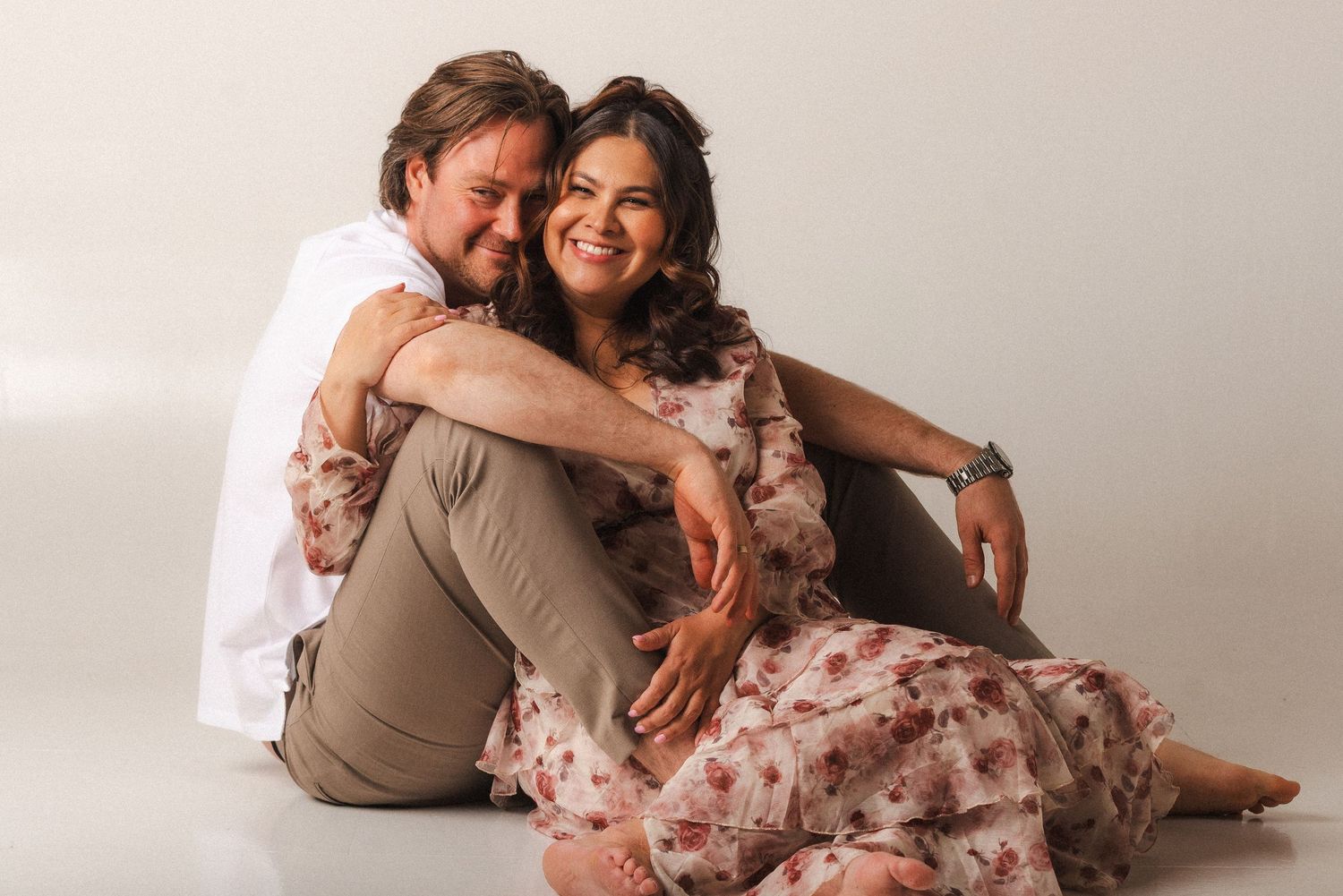 A couple in coordinated beige and pink outfits poses intimately together for a romantic photoshoot.