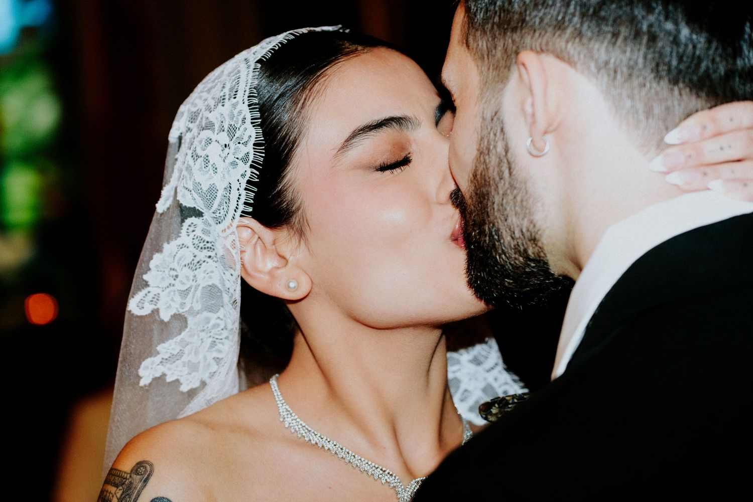 Intimate wedding portrait showing romantic embrace against dark background.