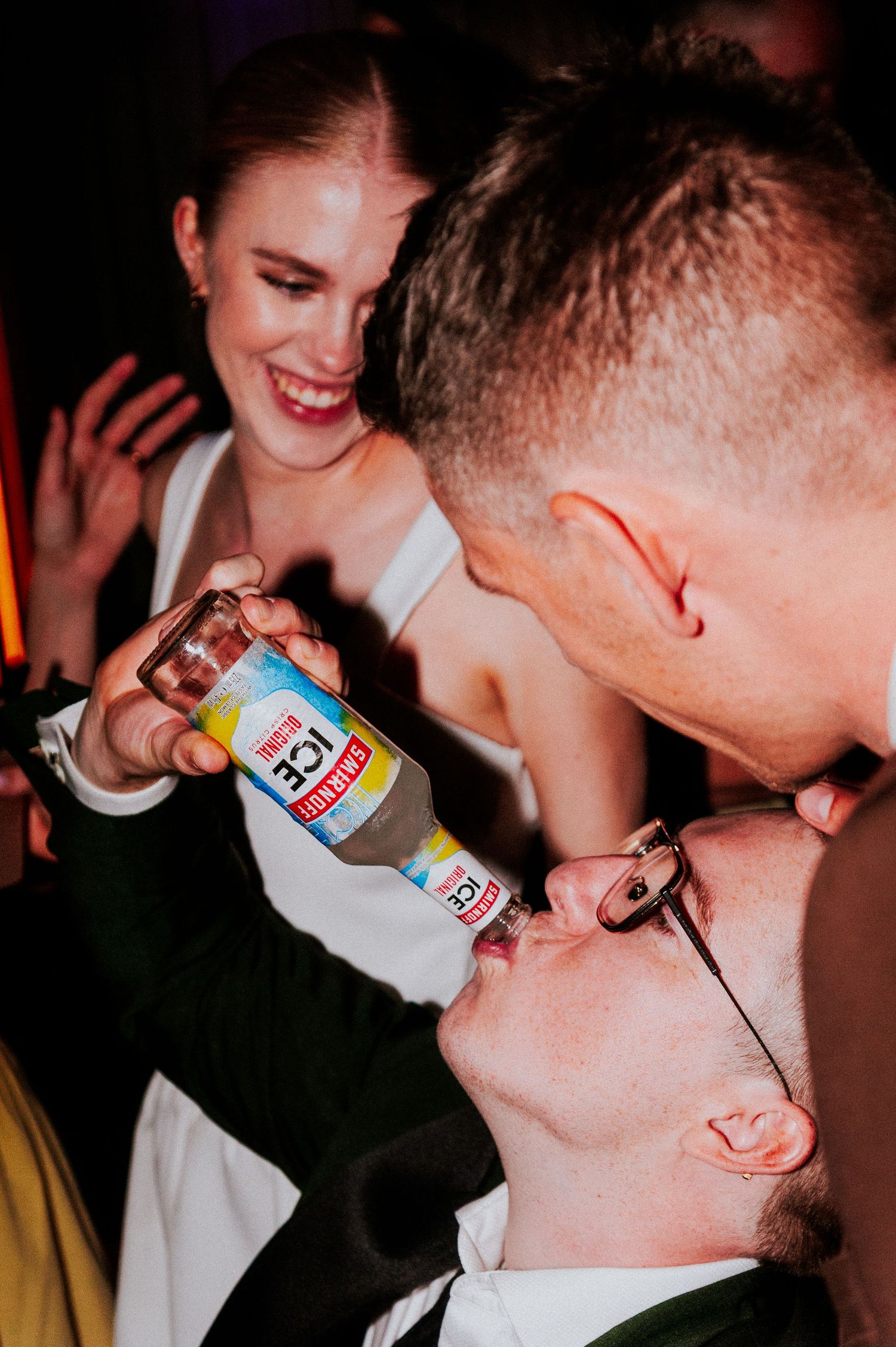 Wedding celebration moment showing guests pouring drinks and sharing laughter at reception party.