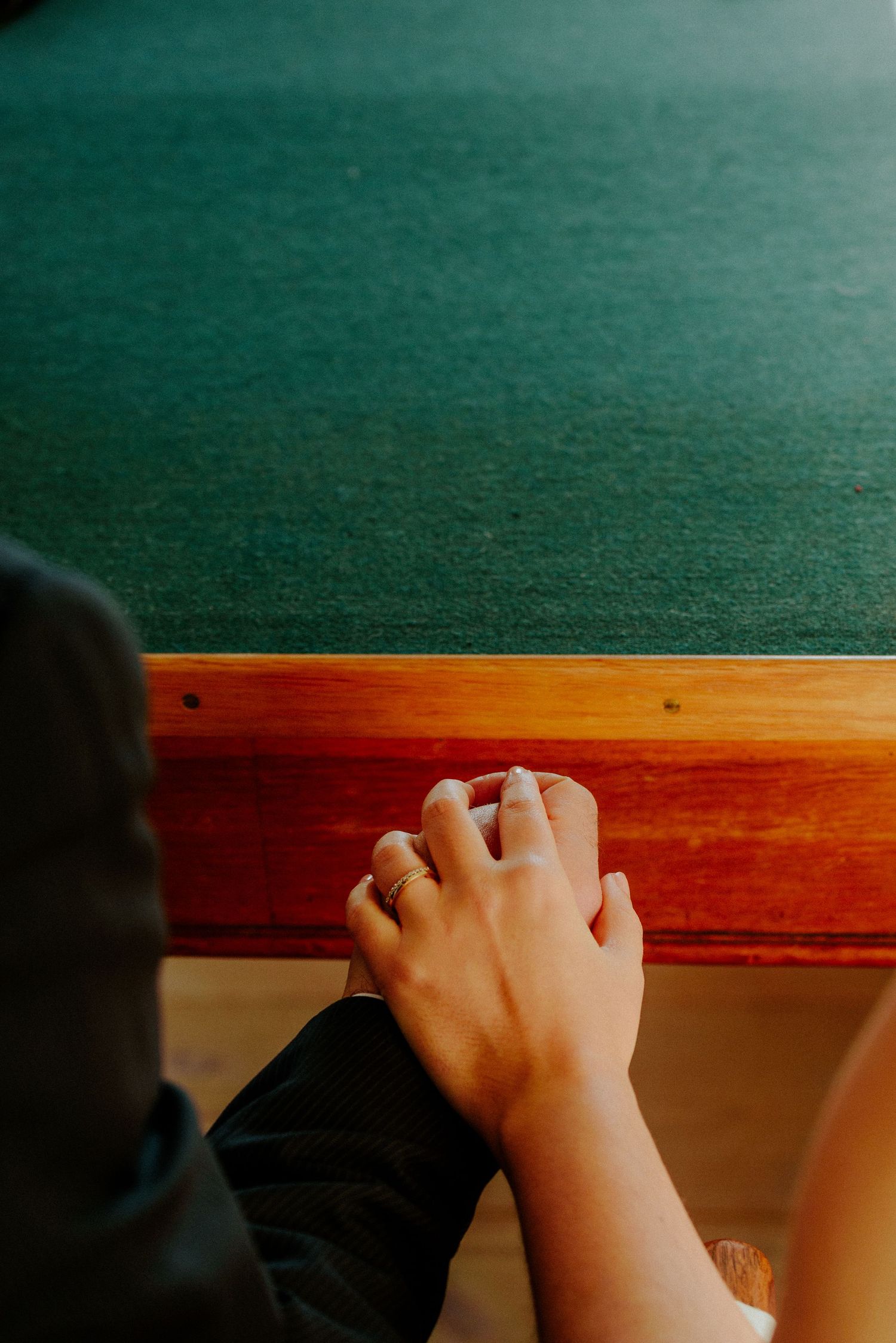 Close-up shot of hands gripping a wooden ledge or bar in a dimly lit setting.
