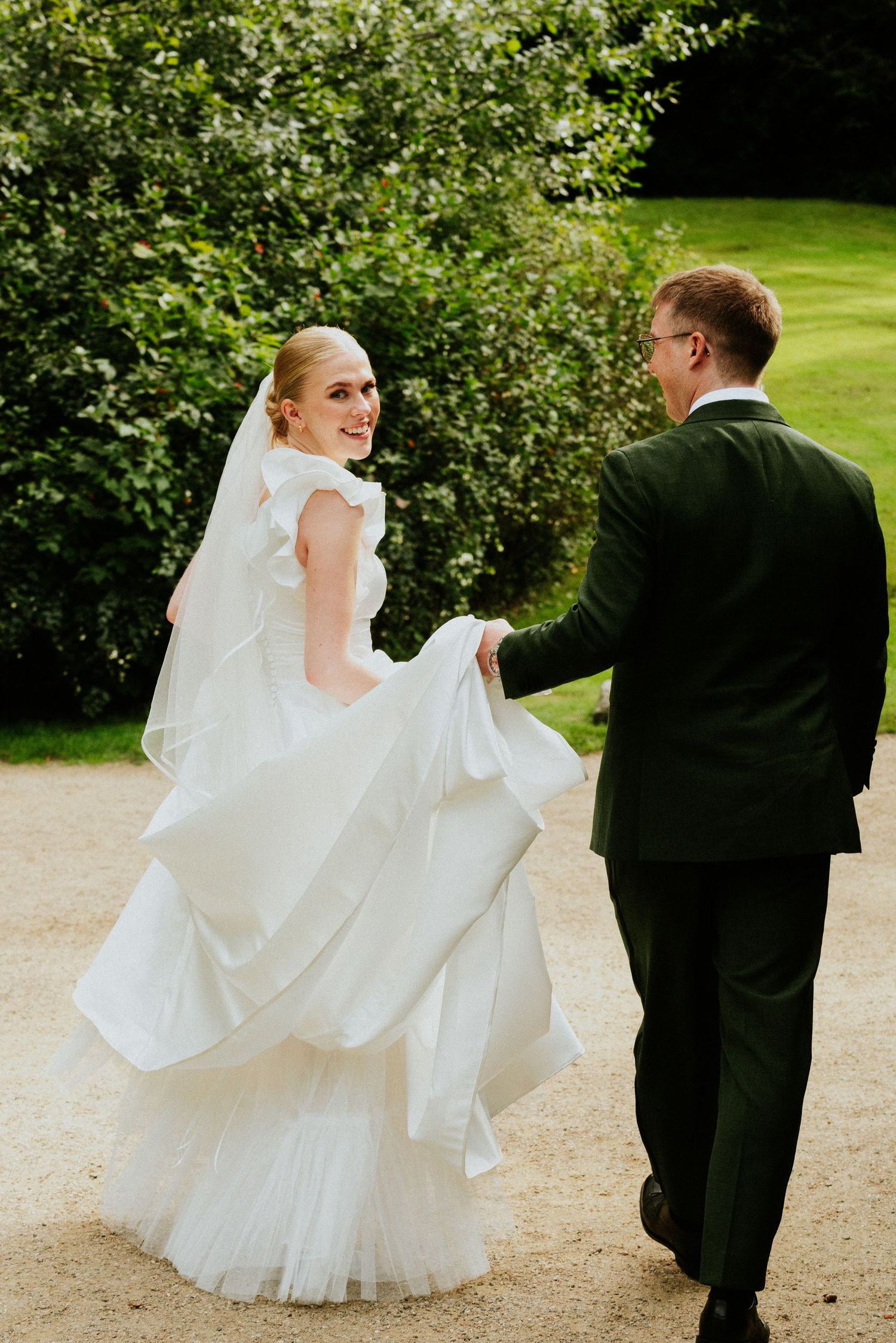 A series of outdoor wedding photos showing a flowing white dress and formal attire on a garden path.