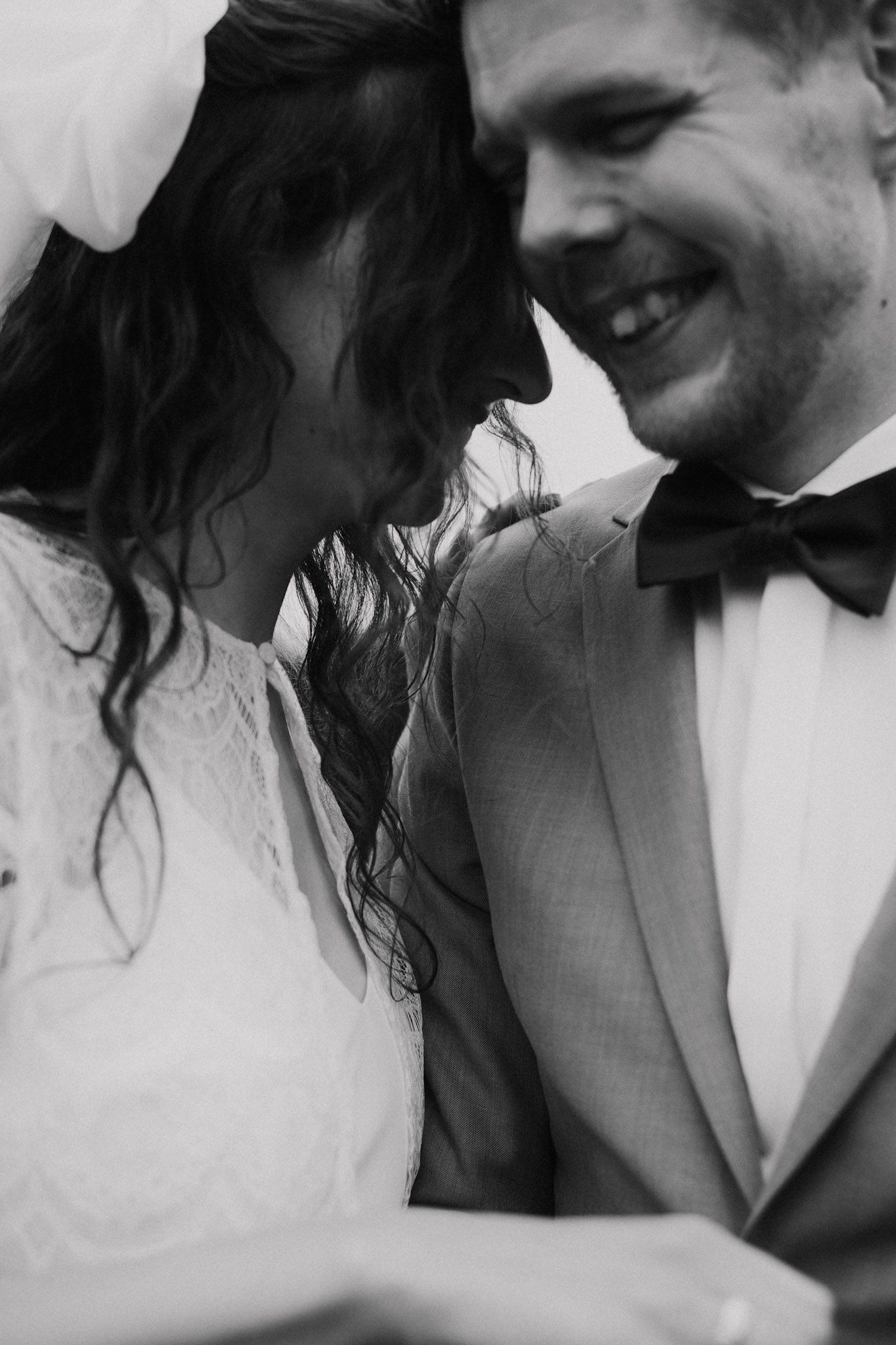 Black and white intimate moment between newlyweds sharing laughter during their wedding celebration.