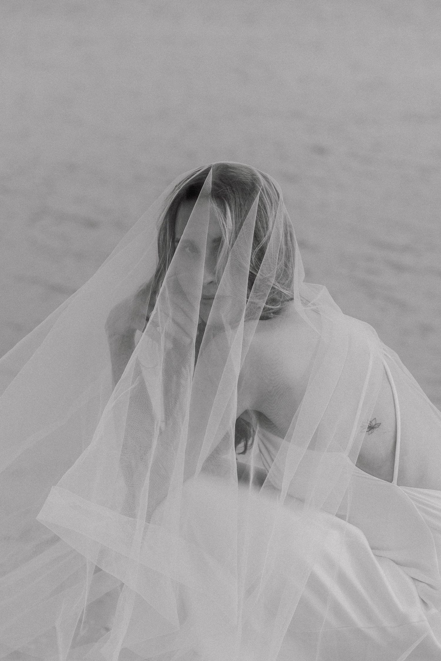 Black and white artistic portrait series showing ethereal movement of a delicate white veil in the wind.