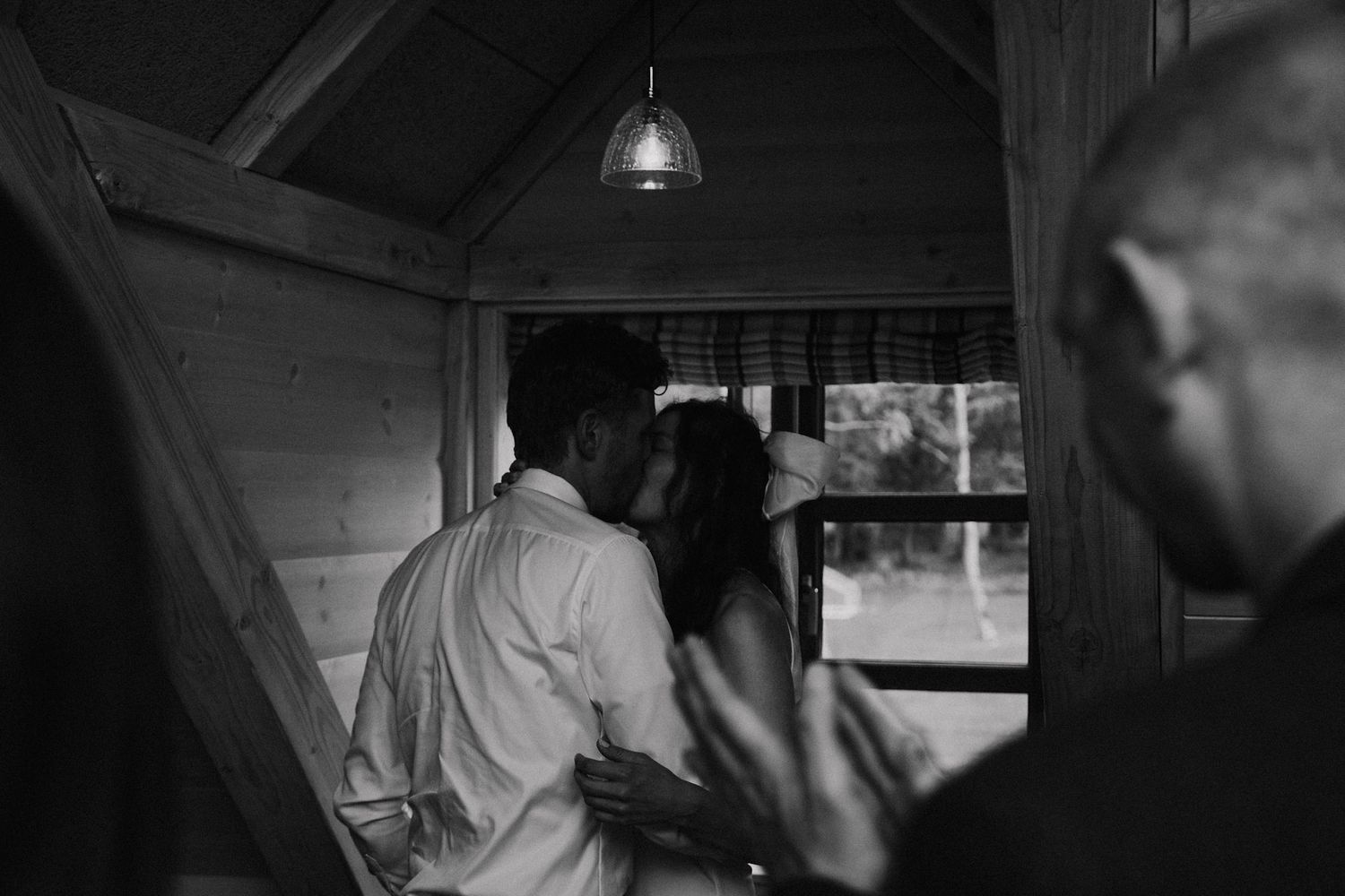 Black and white candid shot of couple in rustic venue with ambient lighting.