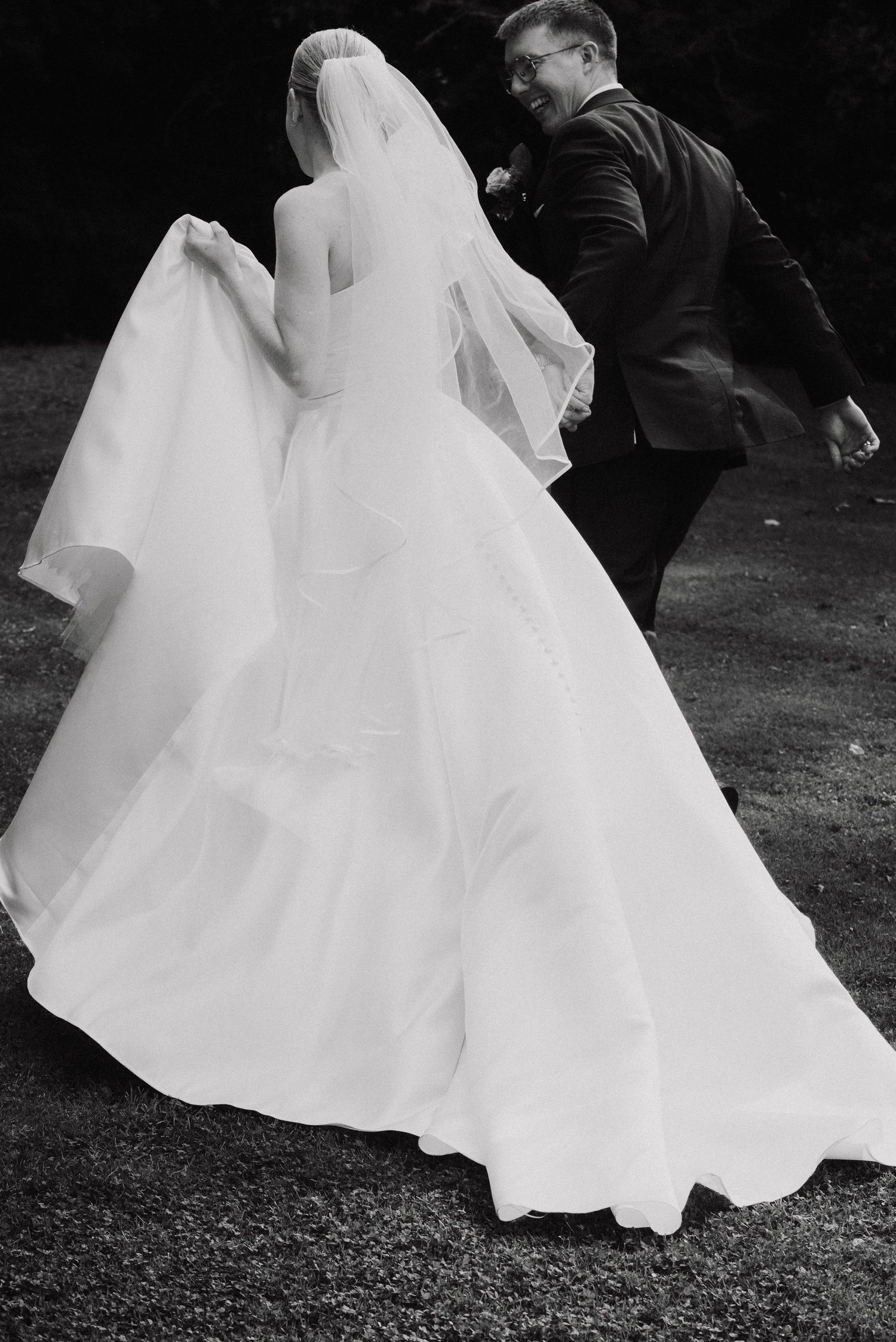 Flowing white wedding dress creates dramatic movement in black and white photography.