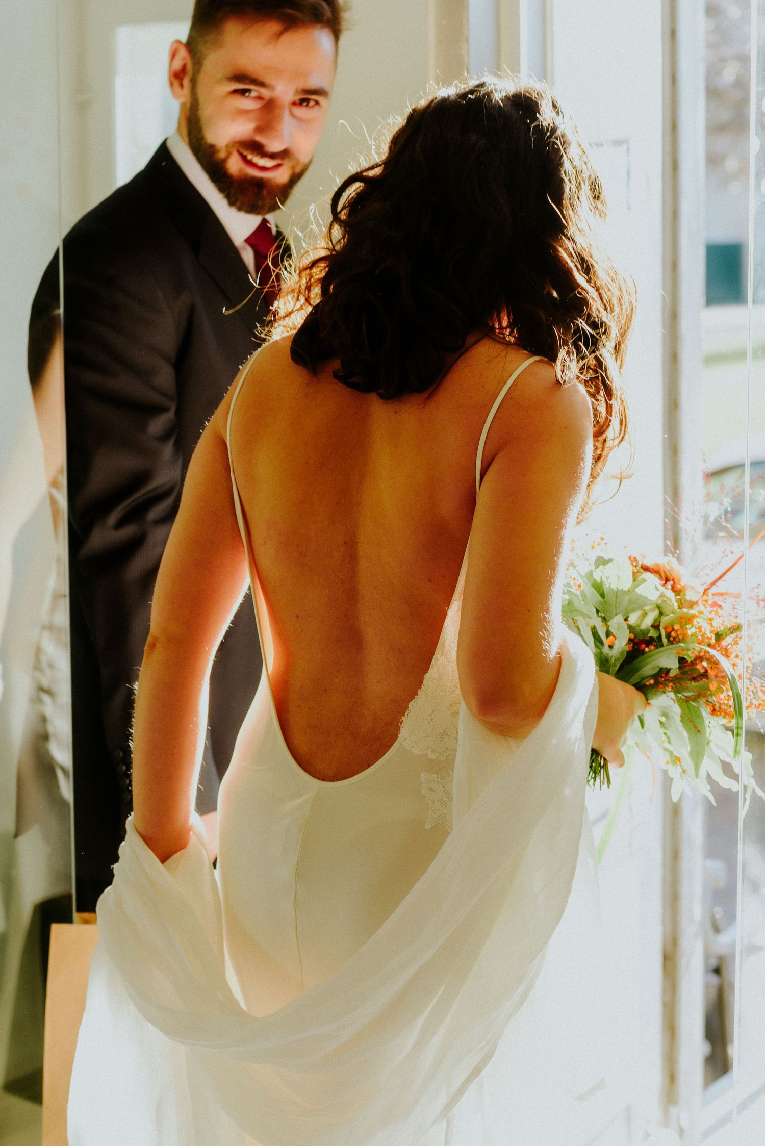 Bride in white wedding dress laughs joyfully during candid moment at indoor venue.