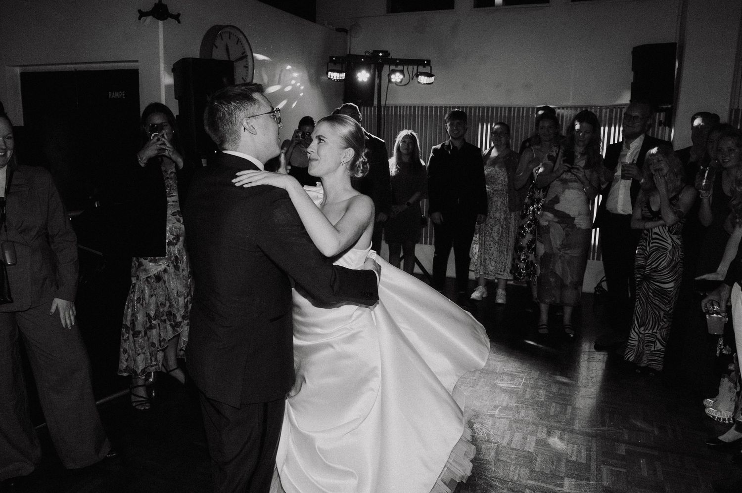 A couple shares their first dance at a wedding reception while guests watch from the dance floor.