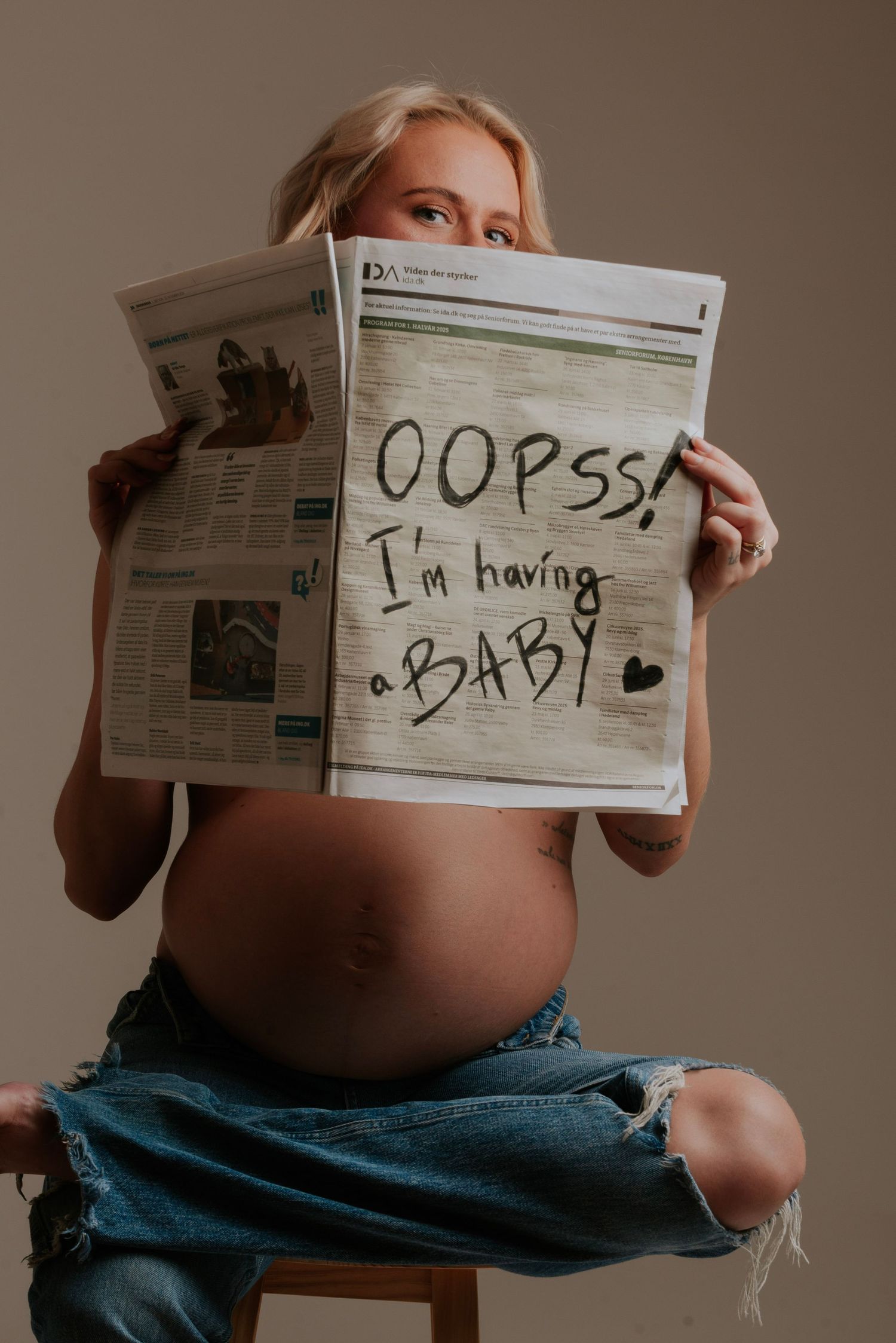 A series of photos showing a pregnant belly with handwritten signs held against a newspaper background.