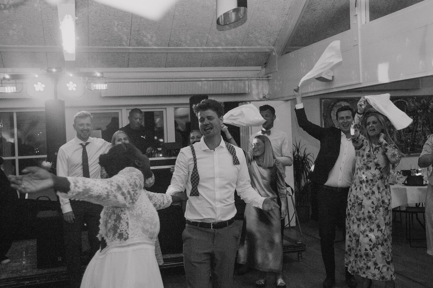 Black and white photo capturing joyful dancing at a wedding reception.