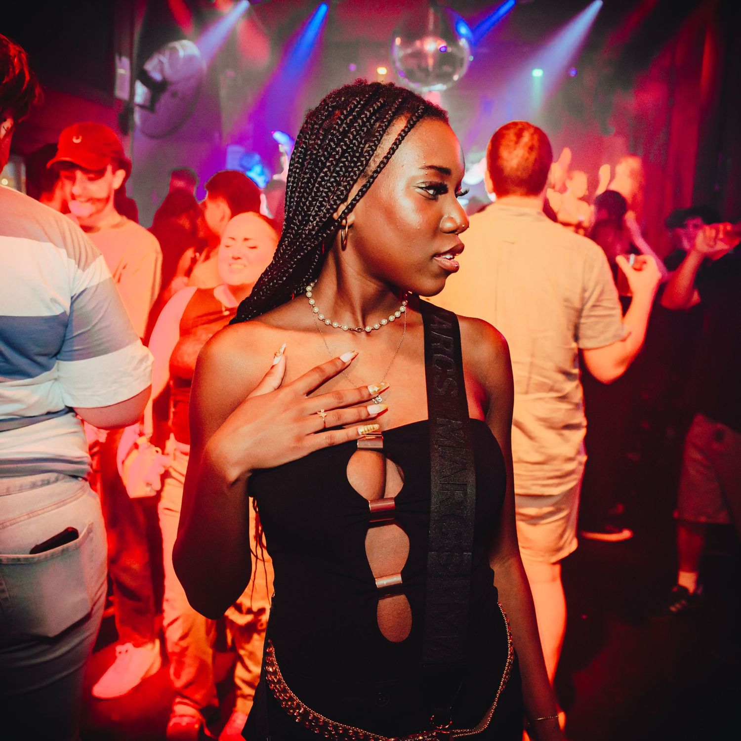 Partygoers dancing and enjoying a vibrant nightclub atmosphere with dramatic red and blue lighting effects.