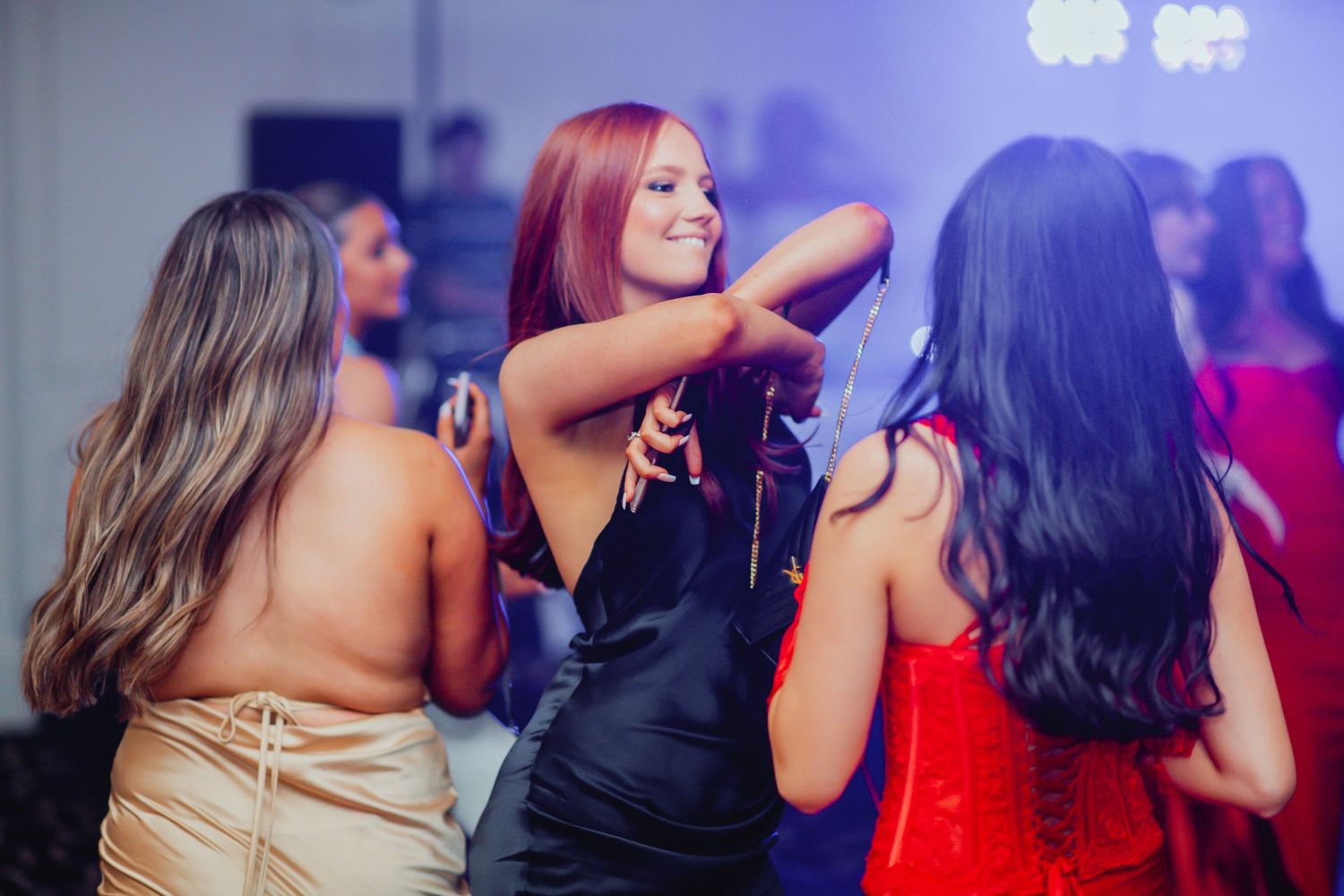 Friends enjoy dancing together at a nightclub with purple lighting and a festive atmosphere.