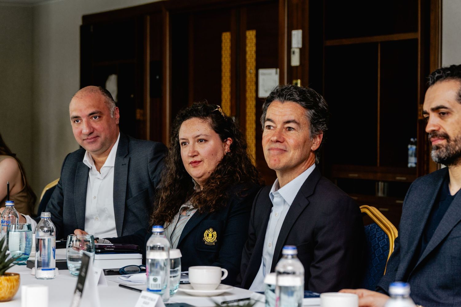 Business professionals seated at a conference table during a formal meeting or corporate event.