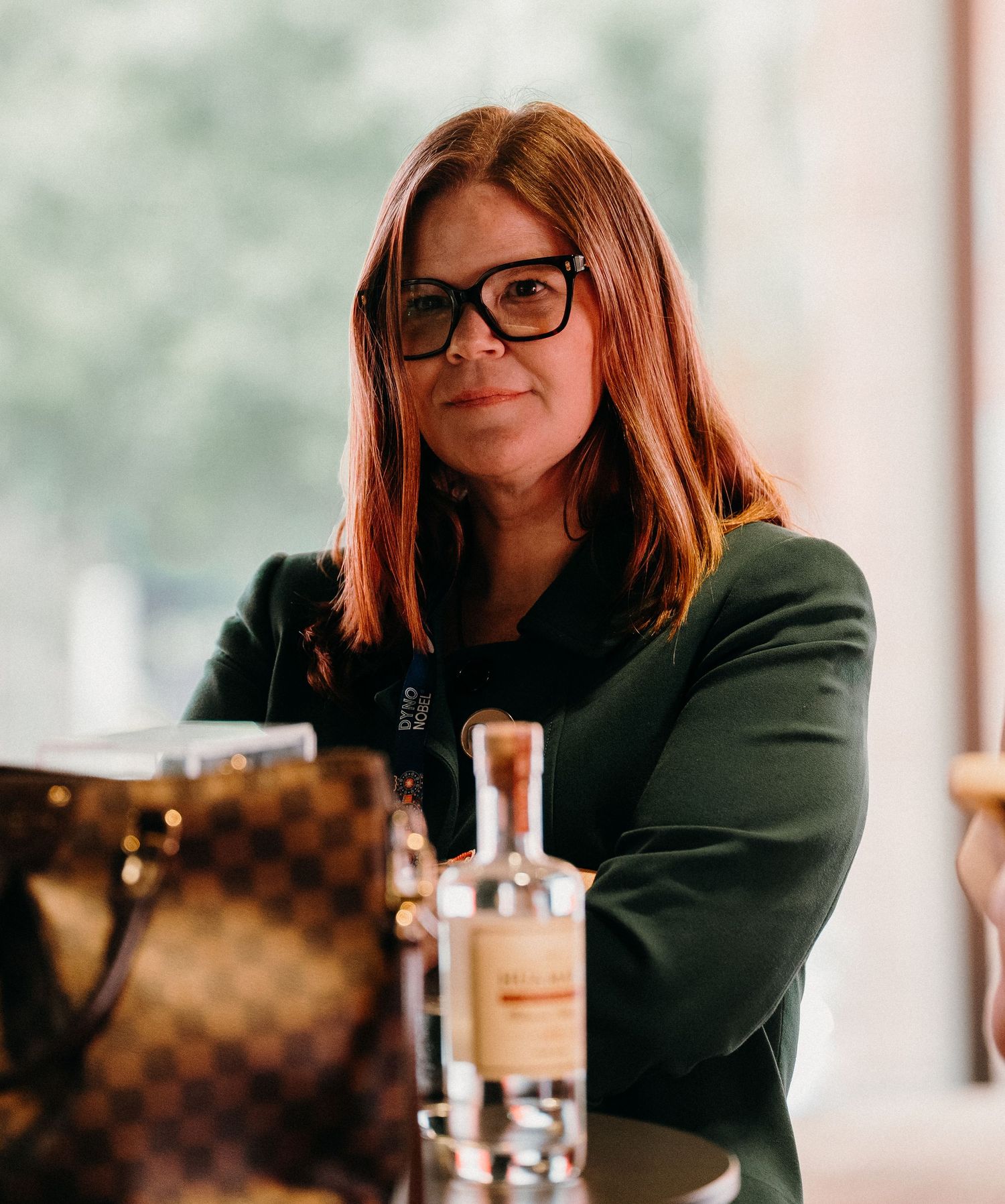 Person in dark blazer and glasses sits at a table in a series of candid shots.