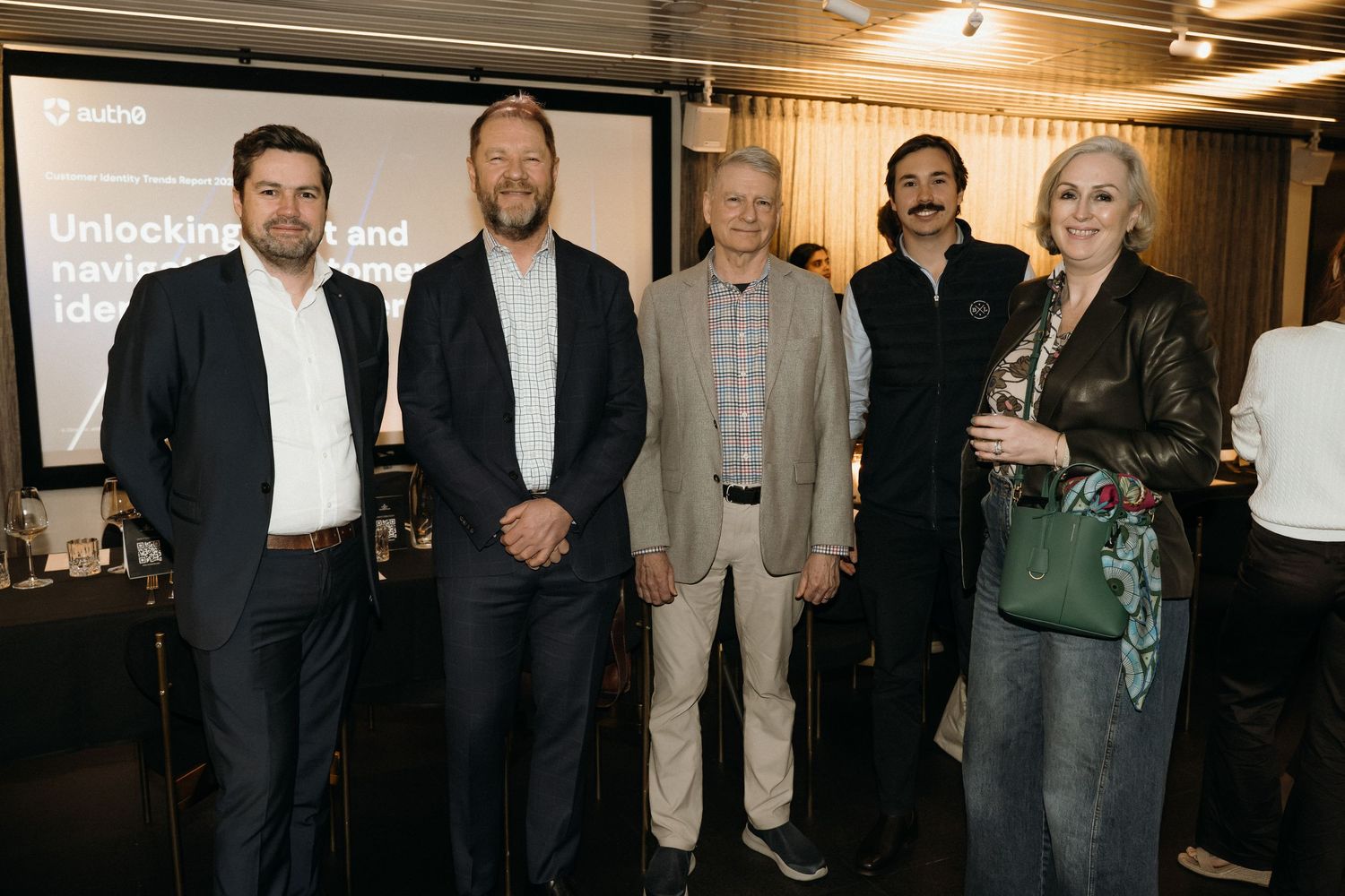 A group of professionals stand together at a business networking event in an indoor venue.