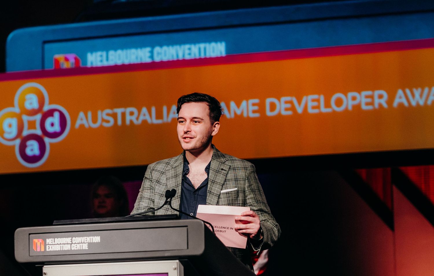 A speaker presents at the Australian Game Developer Awards ceremony on stage at the Melbourne Convention.
