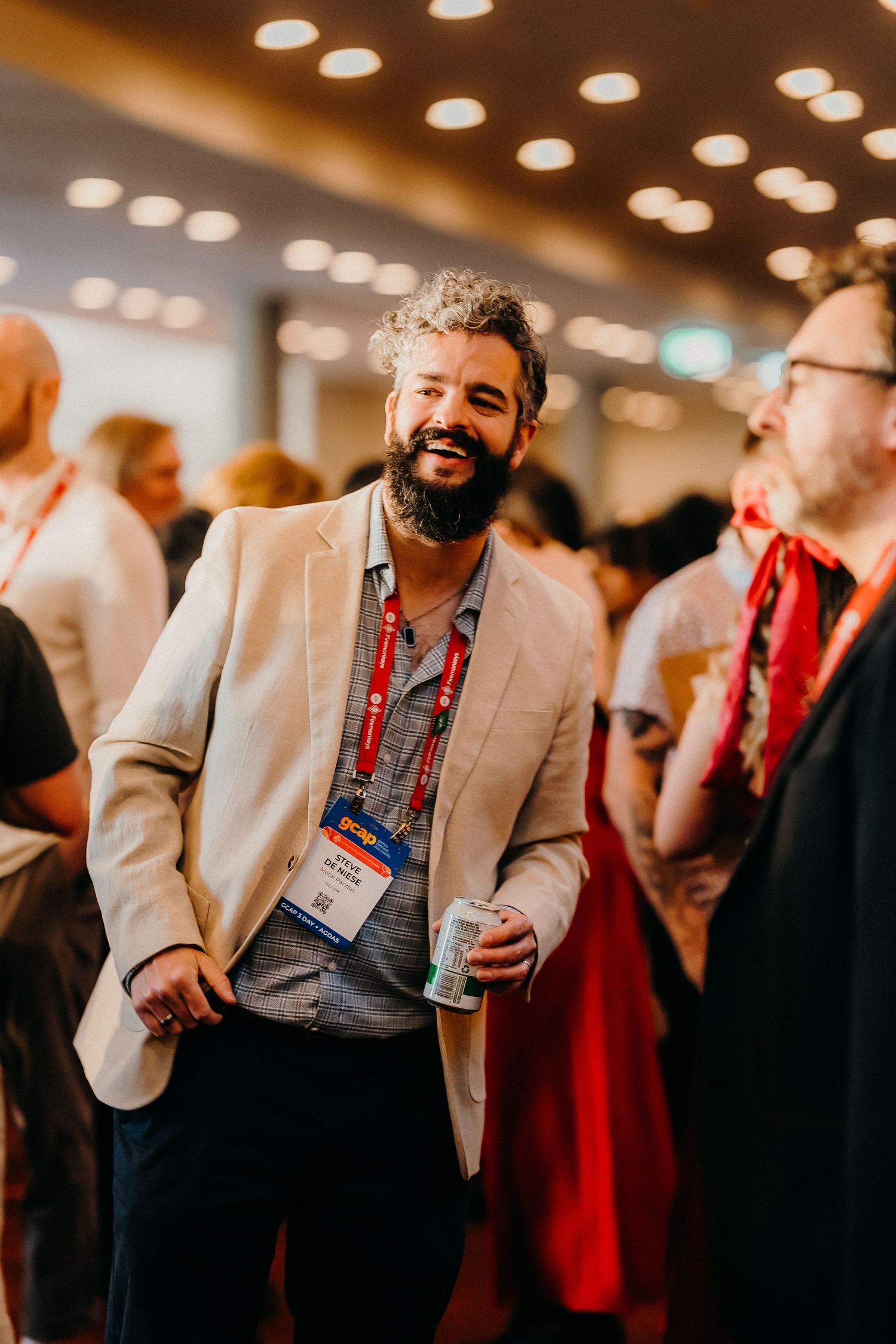 People in business attire networking and socializing at a professional conference with warm lighting overhead.