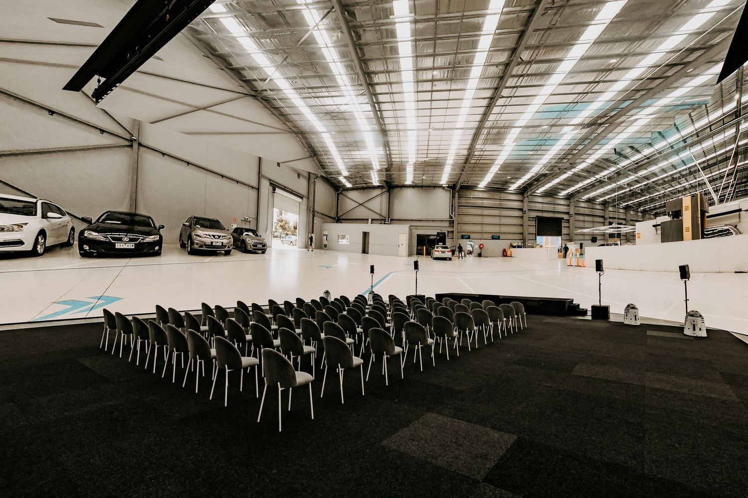 A panoramic view of a large empty conference room with rows of black chairs under industrial lighting.