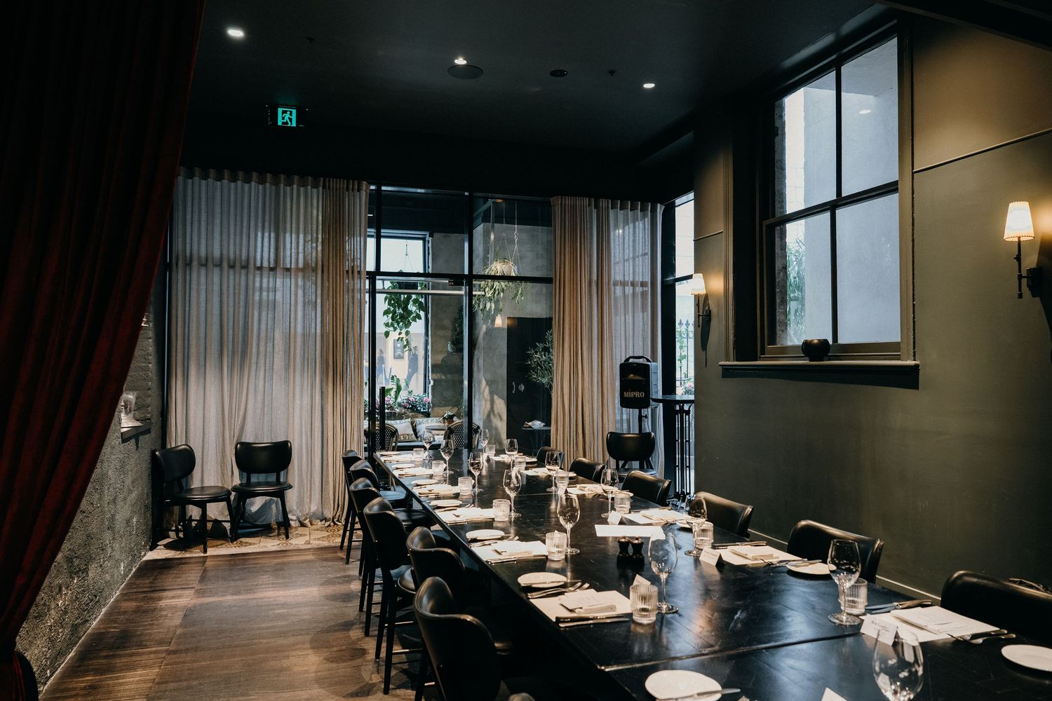 Modern restaurant interior with dark walls features elegant dining tables and ambient lighting creating an intimate atmosphere.