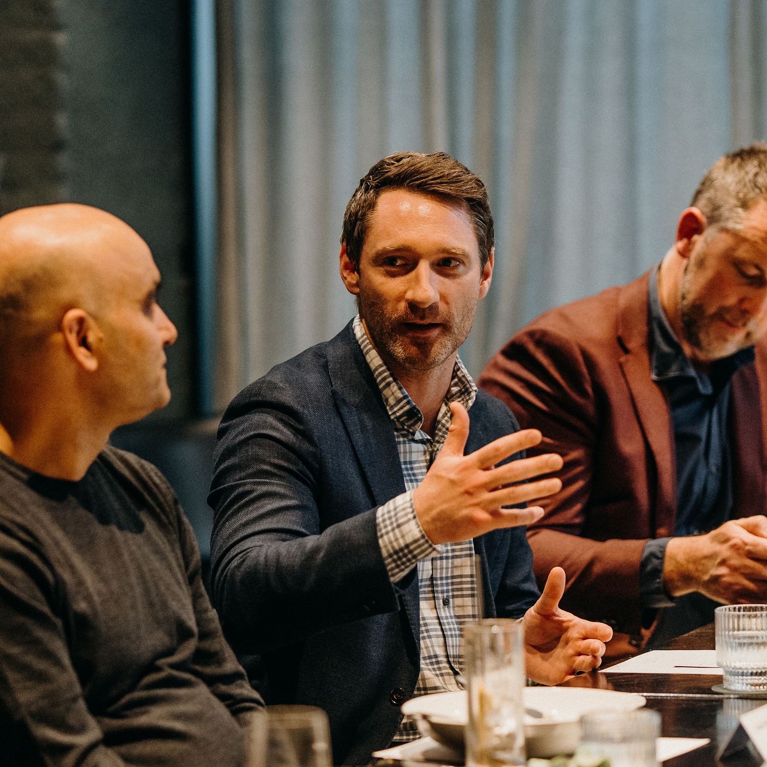 Business professionals engaged in an animated discussion during a meeting around a conference table.