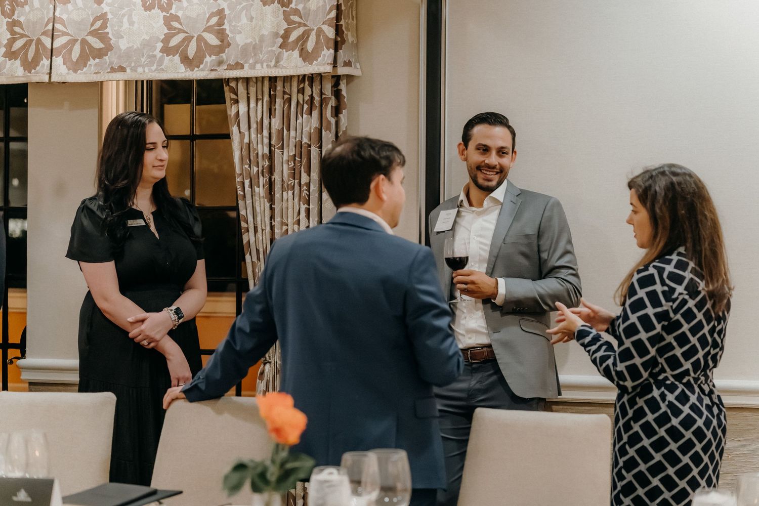 A group of people networking and mingling at a professional business event in a bright indoor space.