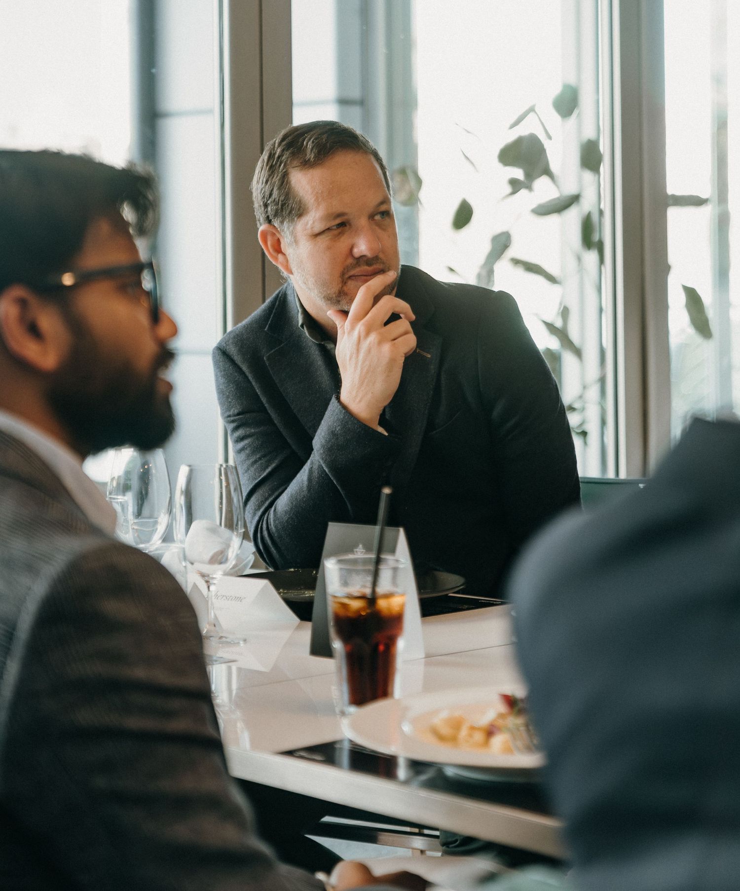 Business professionals having a discussion during lunch meeting at a bright restaurant with window views.