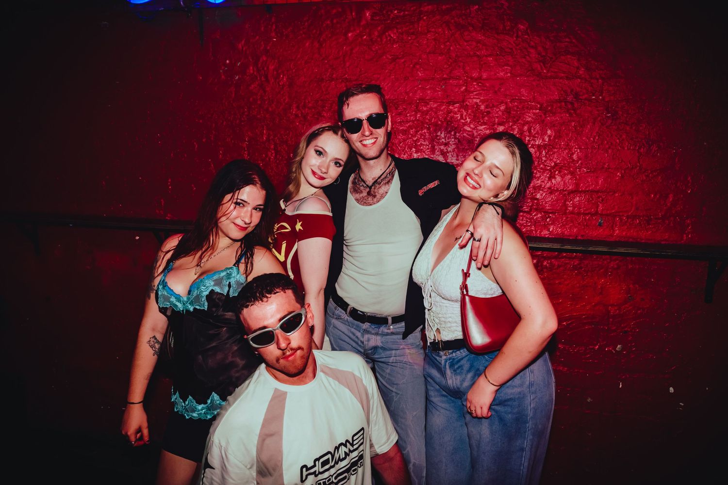 People having fun at a nightclub with red mood lighting and casual attire.
