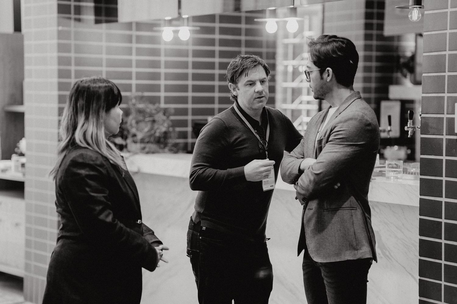 People gather and chat in small groups outside a brick building on a winter day.