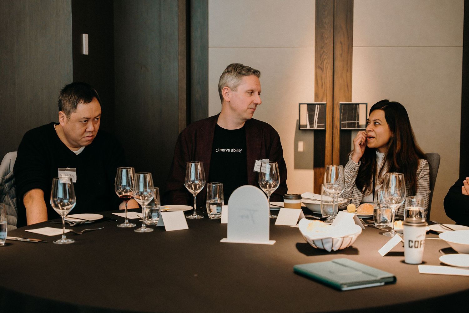 People seated around a dining table with wine glasses and place settings during an upscale business dinner meeting.