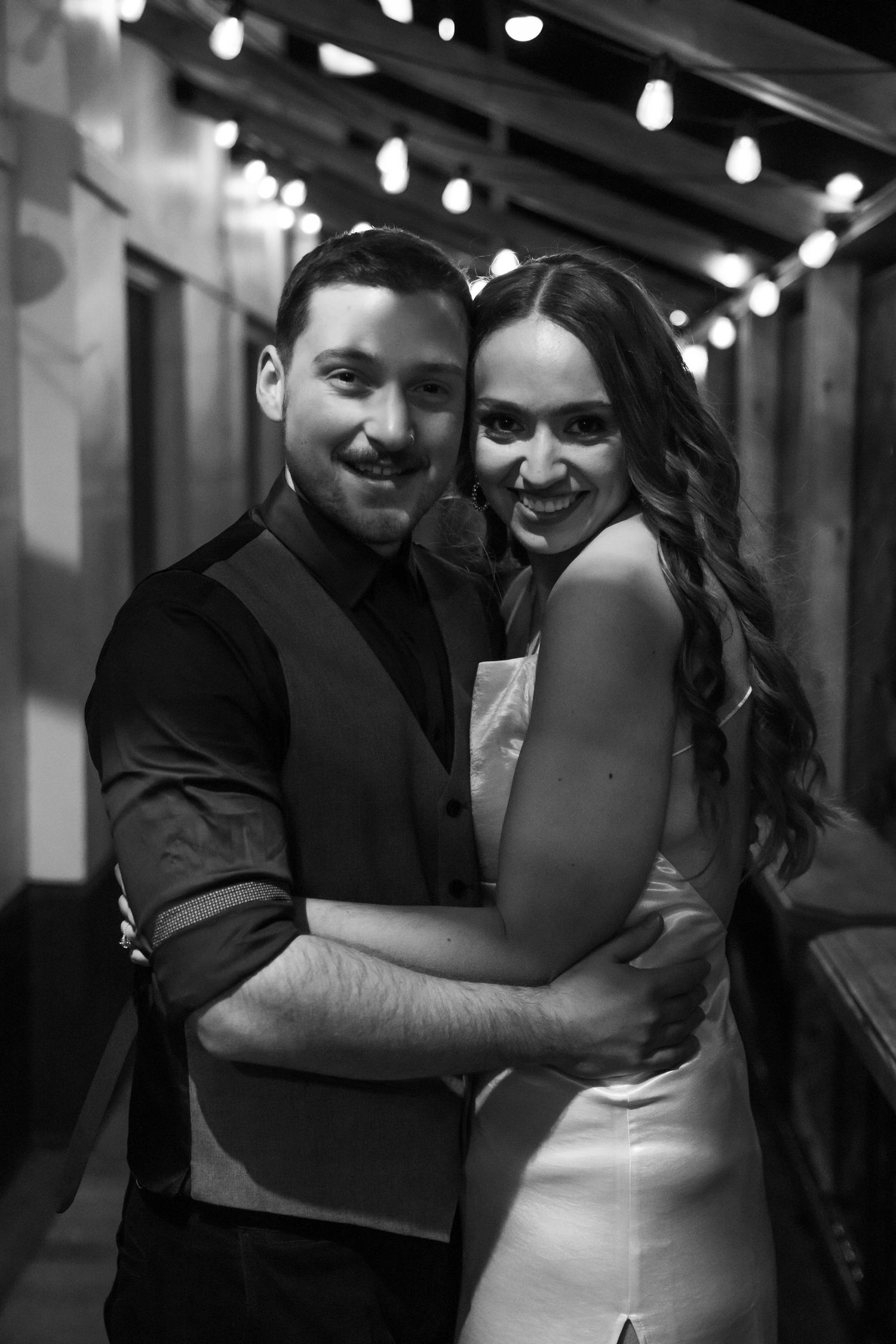 A couple shares intimate embraces and smiles in formal attire during what appears to be a wedding celebration.