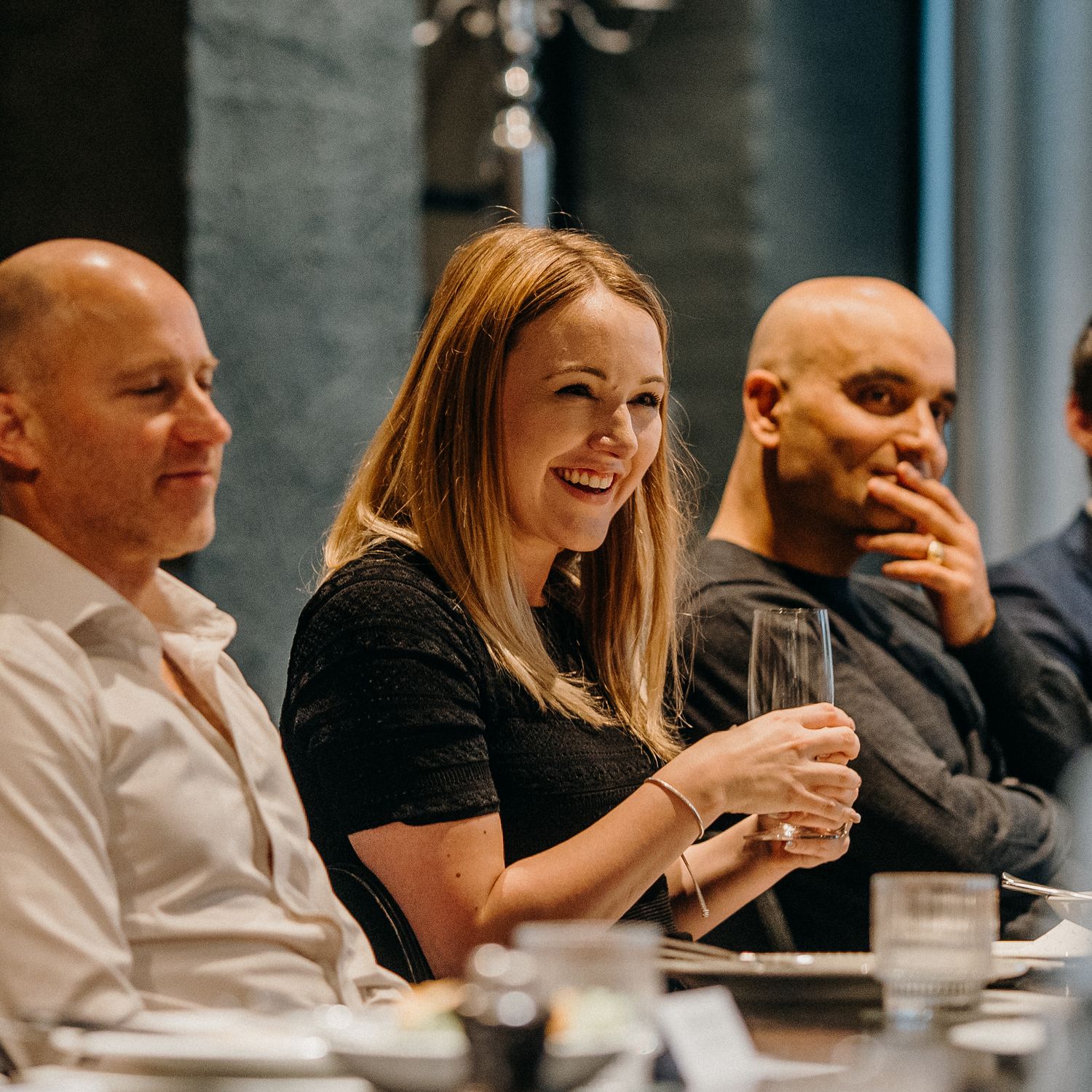A group of colleagues enjoying drinks and conversation at a casual business dinner gathering.
