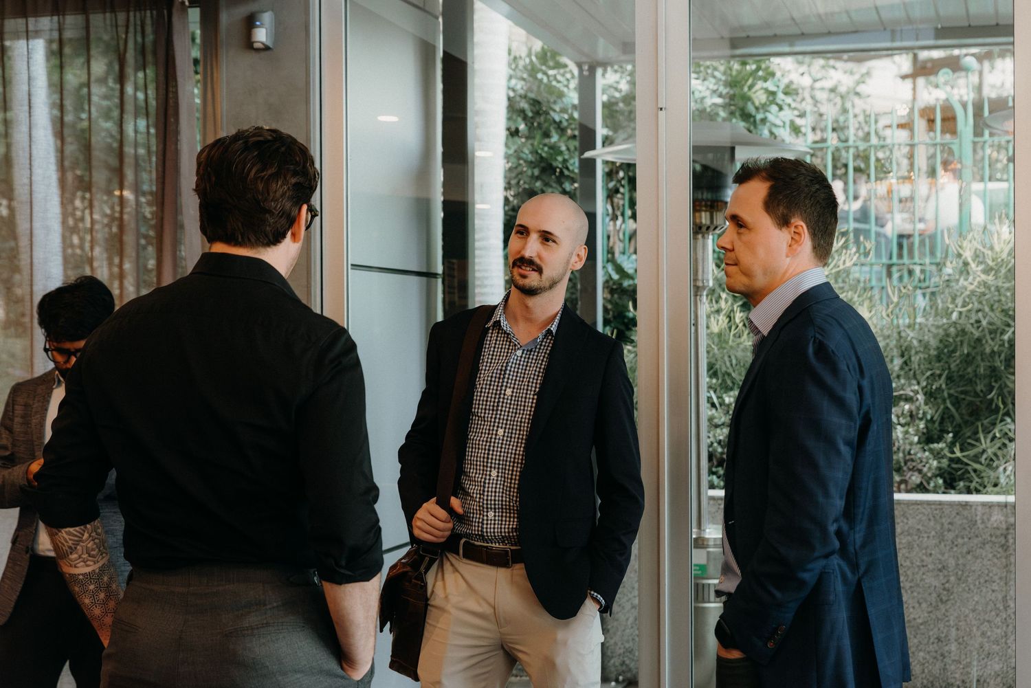 Business professionals gather in a modern office space with glass walls and natural lighting.