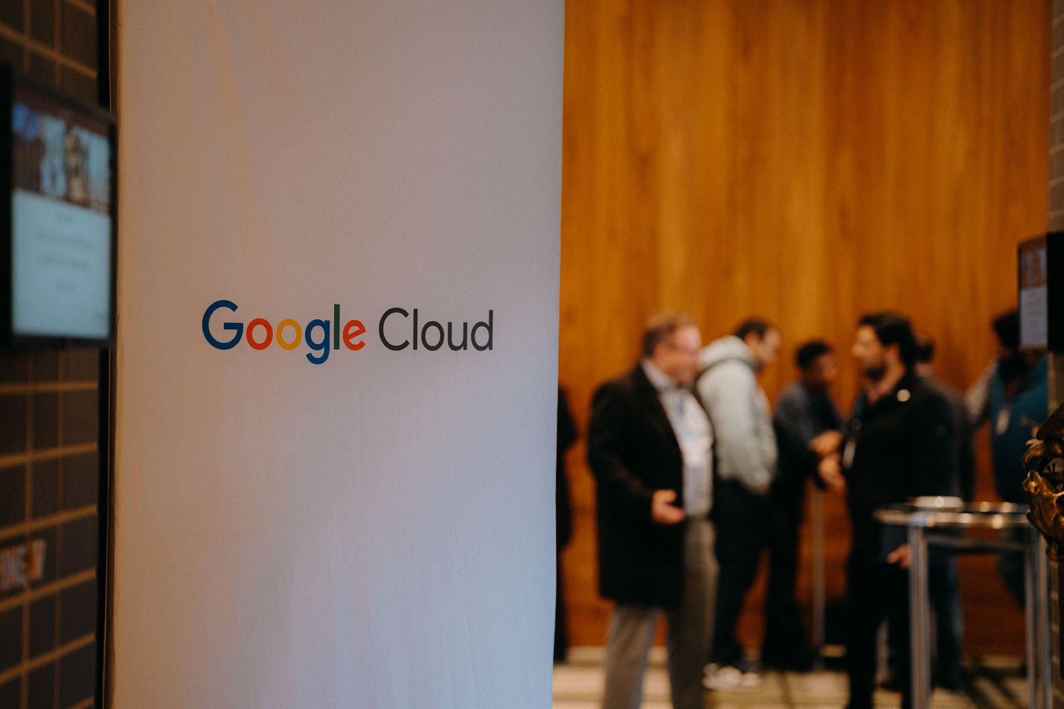 Conference attendees gather in a modern venue with Google Cloud branding visible on the wall.