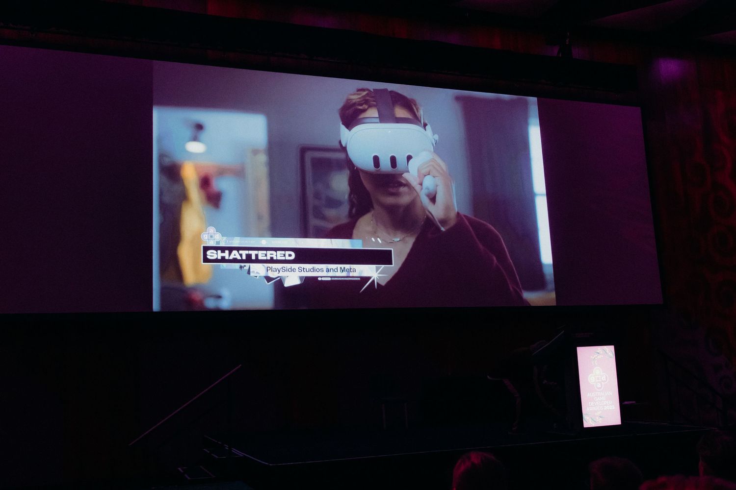 A person wearing a white VR headset illuminated by purple lighting in a dark room.