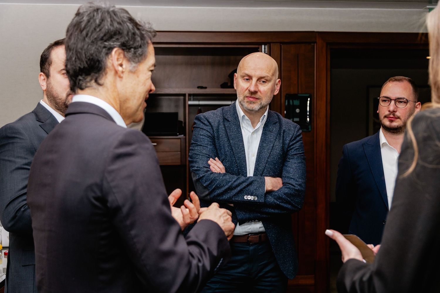 Business professionals in formal attire engaged in a conversation at a corporate networking event indoors.